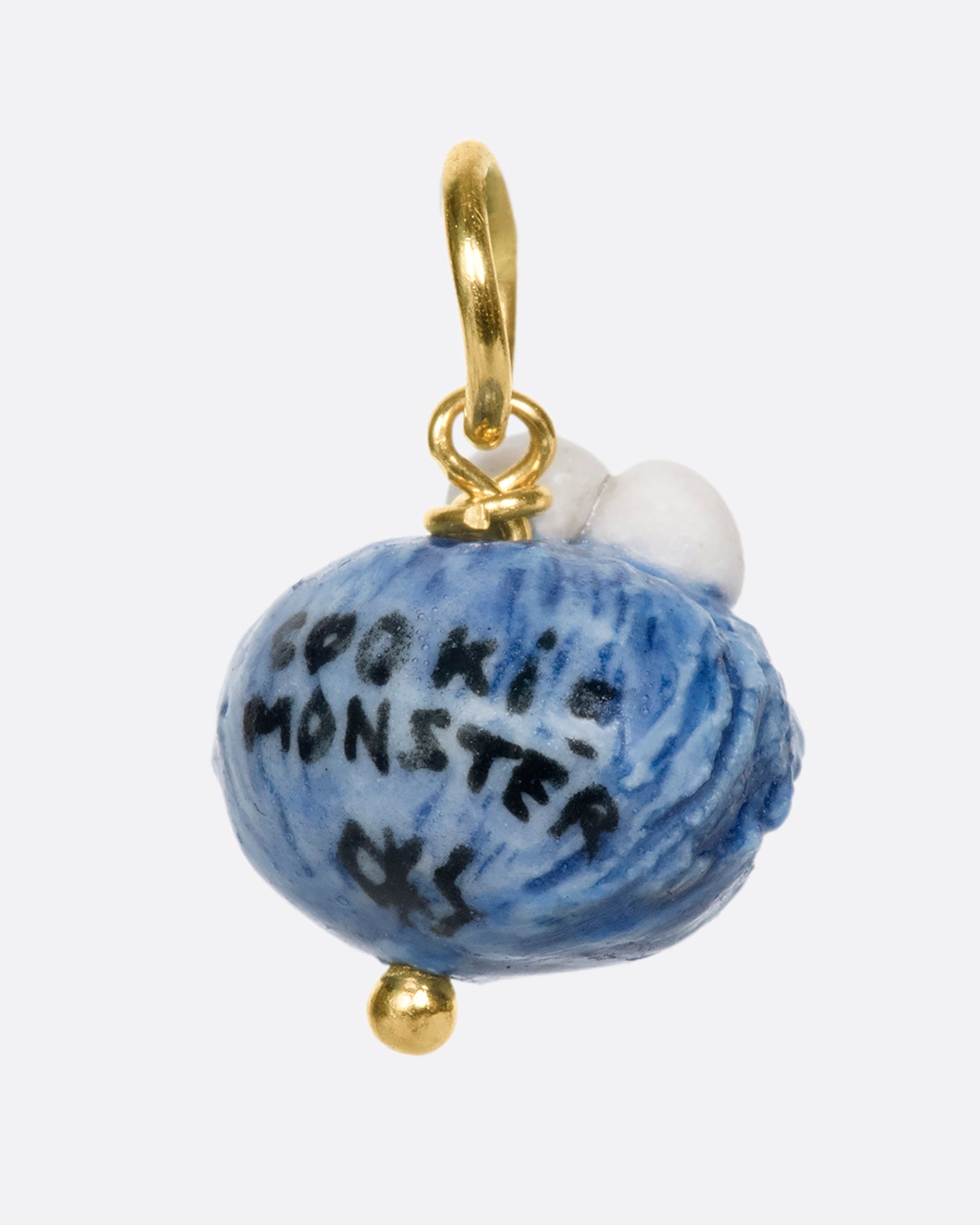 A porcelain Cookie Monster charm on a yellow gold bail.