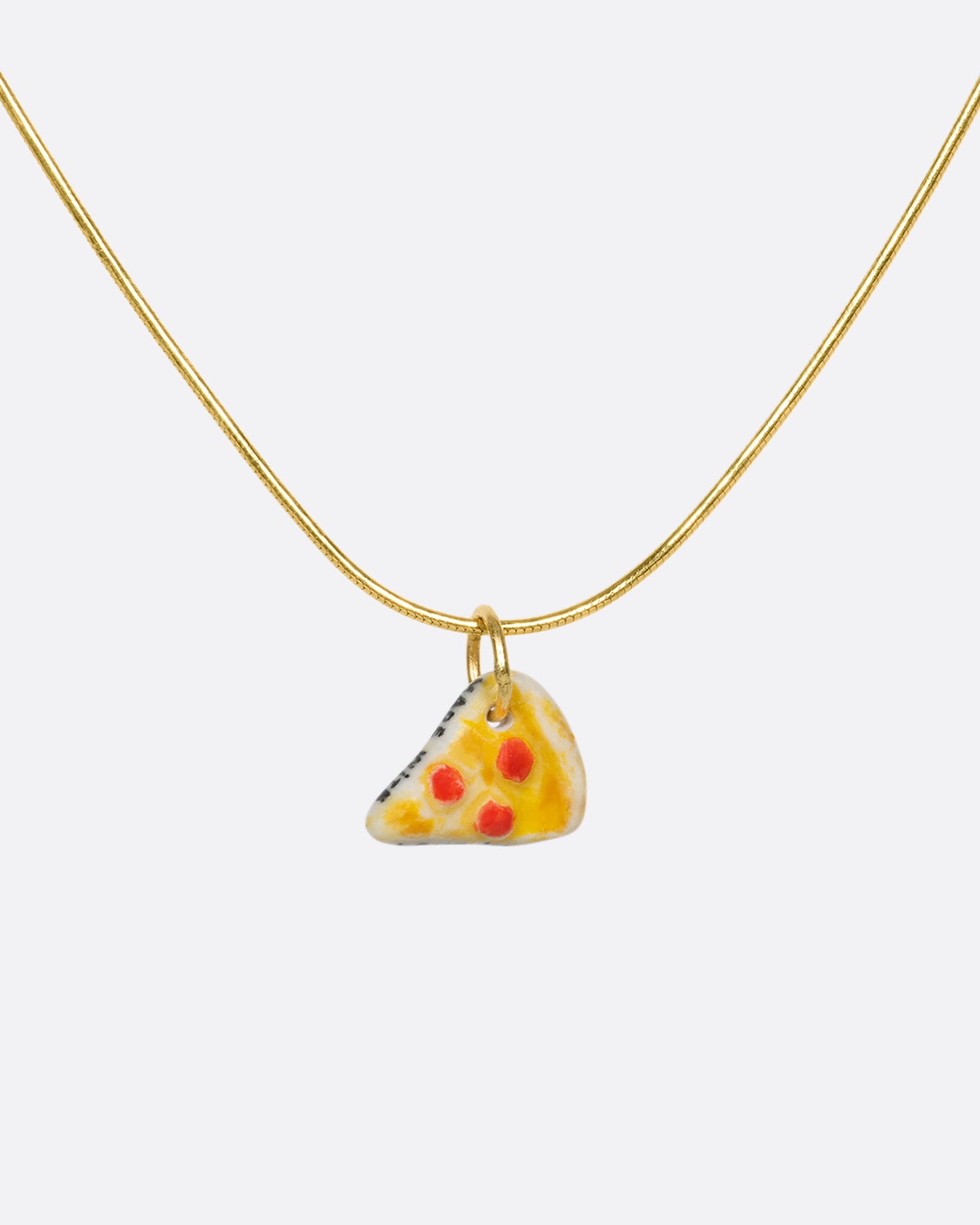 A handmade and painted porcelain pepperoni pizza slice charm with a 14K gold bail.