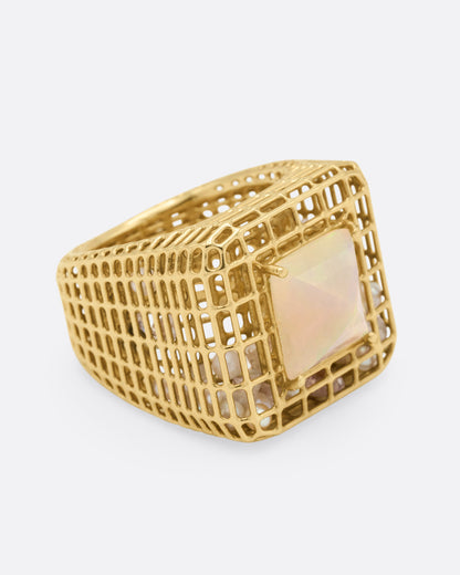 Yellow gold and opal cage ring, side view with the opal facing right and the tapered openwork shank