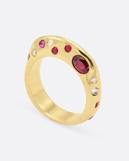 Yellow gold band with scattered rubies and diamonds, tilted view showing stones set across the top of the band