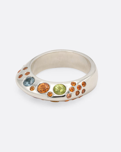 A dimensional sterling silver ring with orange, blue, and pink sapphires on either side, shown from the side.