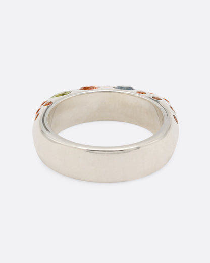 A dimensional sterling silver ring with orange, blue, and pink sapphires on either side, shown from the back.