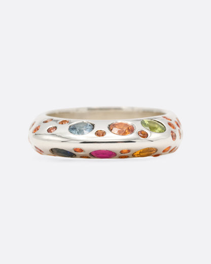 A dimensional sterling silver ring with orange, blue, and pink sapphires on either side, shown from the front.