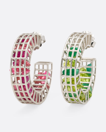 A silver pair of caged hoop earrings filled with loose emeralds, peridots, rubies, and topaz, shown from the front standing up.