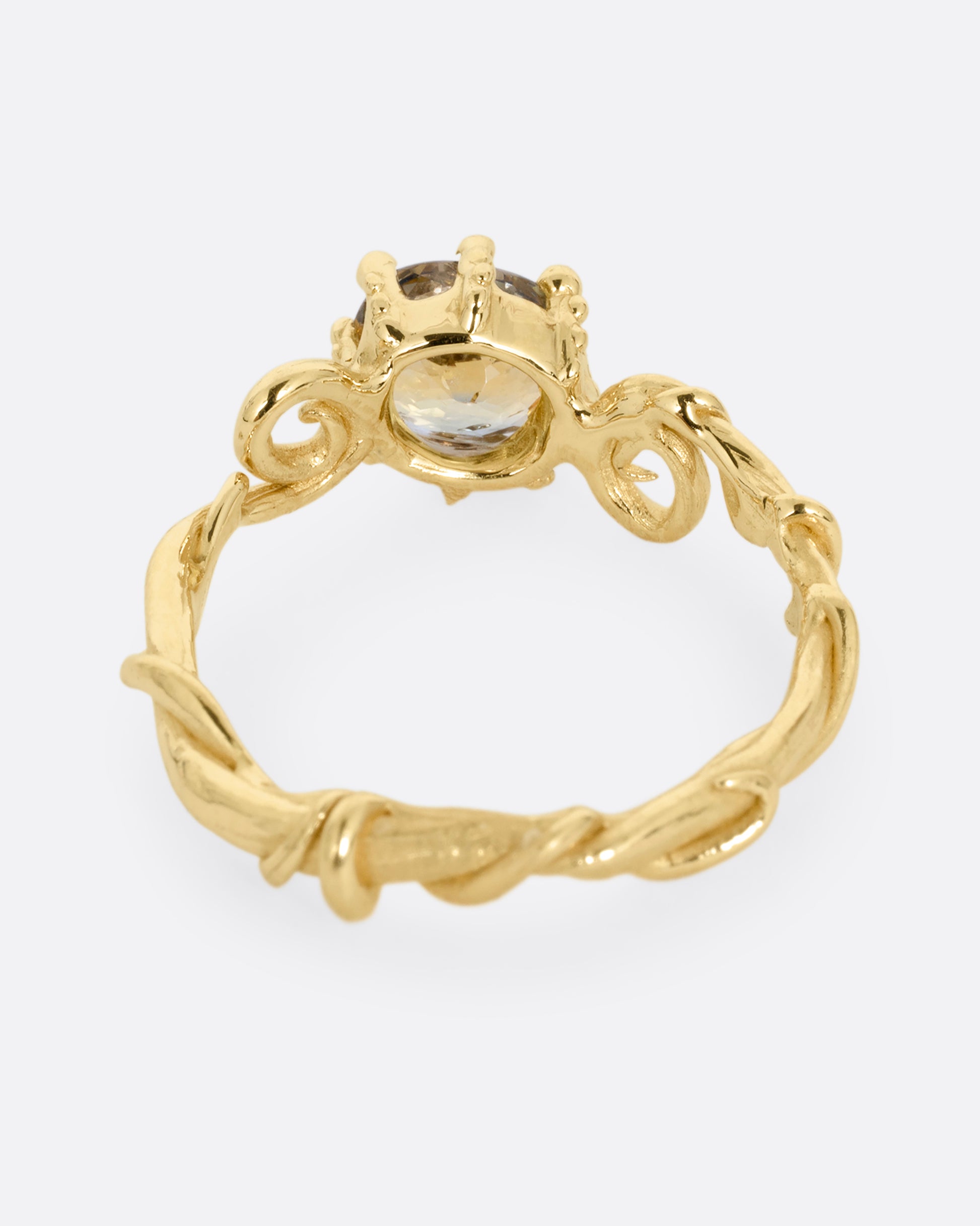 A twisty yellow gold ring with a bicolor sapphire, shown from the back.