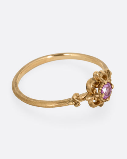 A yellow gold ring with a floral motif and pink tourmaline at the center. Shown from the side.