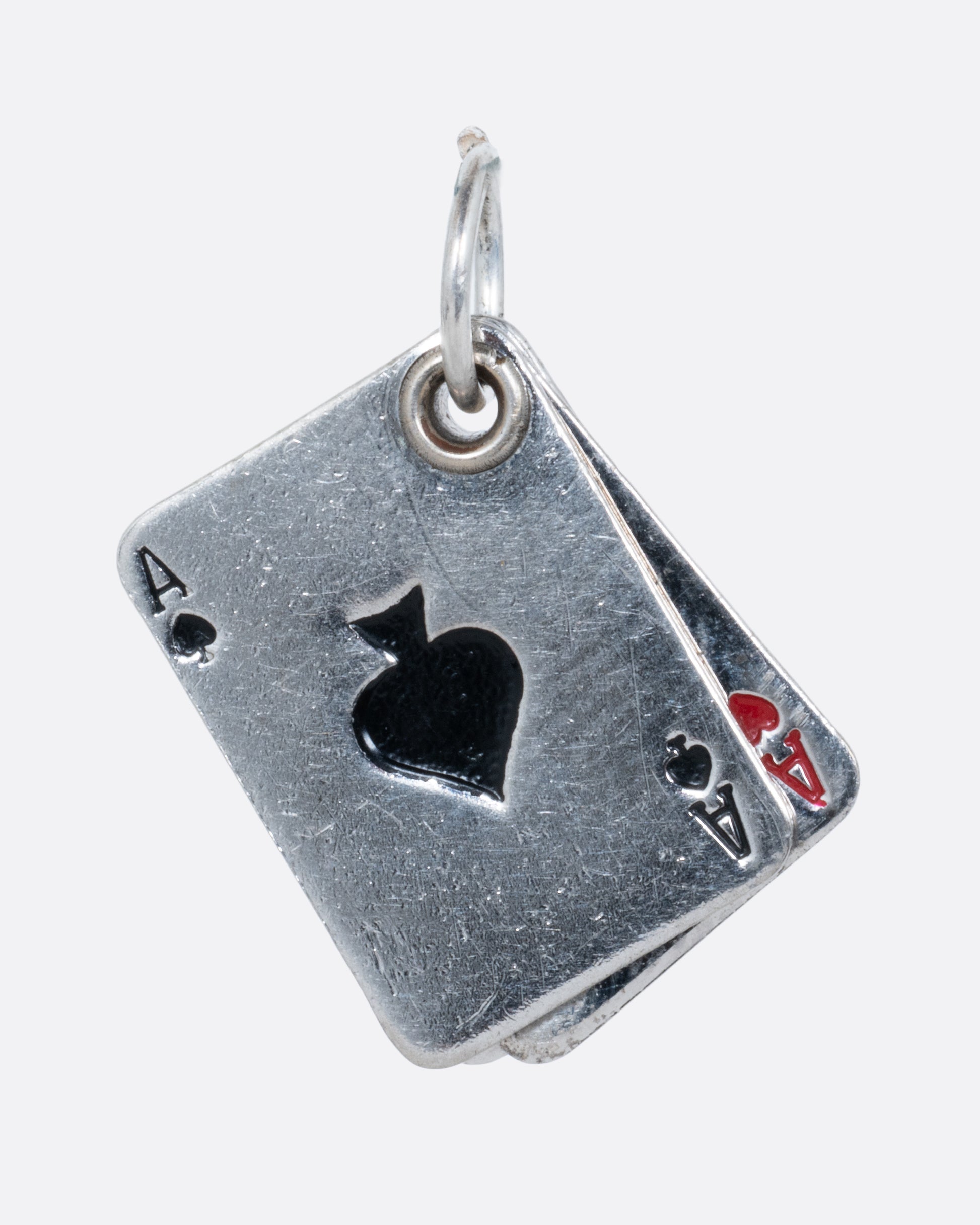 A silver playing card charm with four aces, shown from the front.