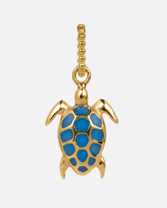 A yellow gold and neon blue enamel miniature sea turtle charm. Shown from the front.