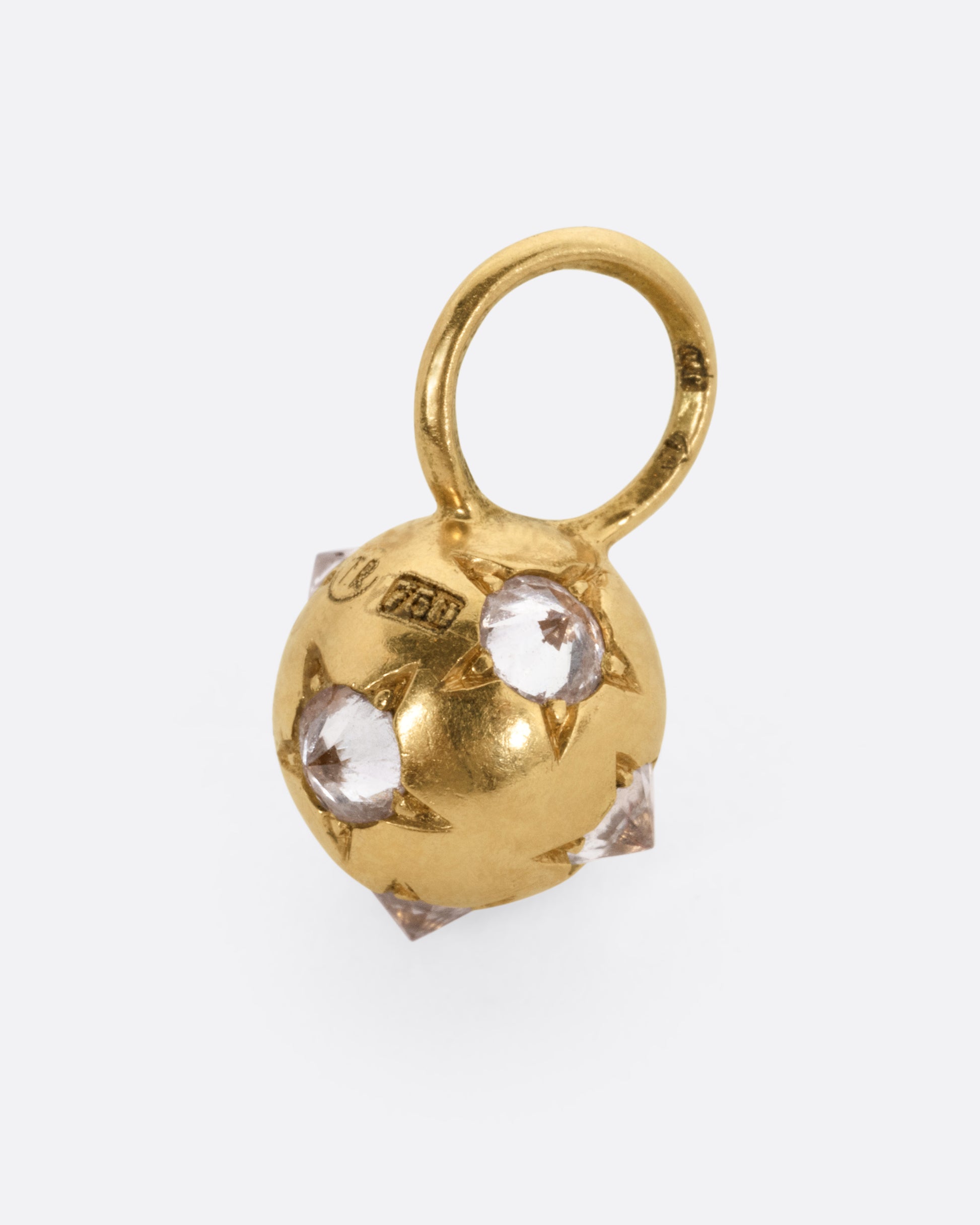 A yellow gold orb shaped charm with reverse set diamonds, shown from the side.