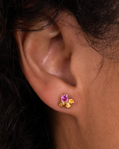 Yellow gold diamond cluster stud earrings, a Starlight stud shown on an ear for scale, in a pink and orange sapphire version