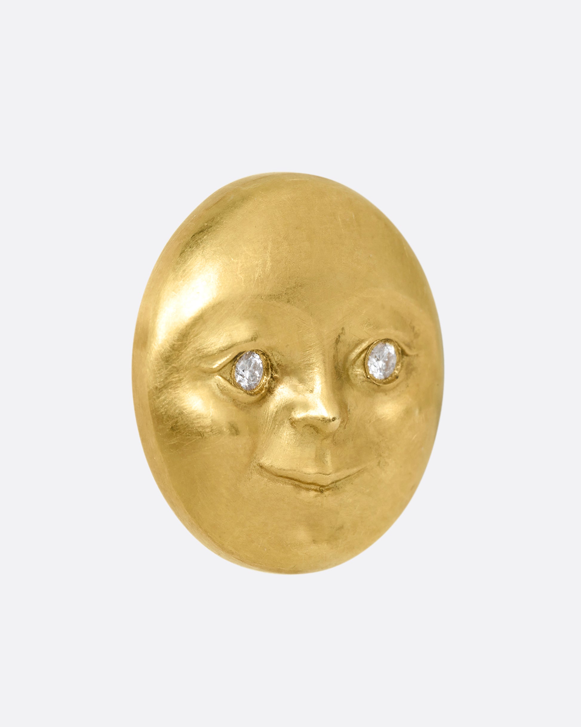 A yellow gold moon face stud earring with diamond eyes. Shown from the side.