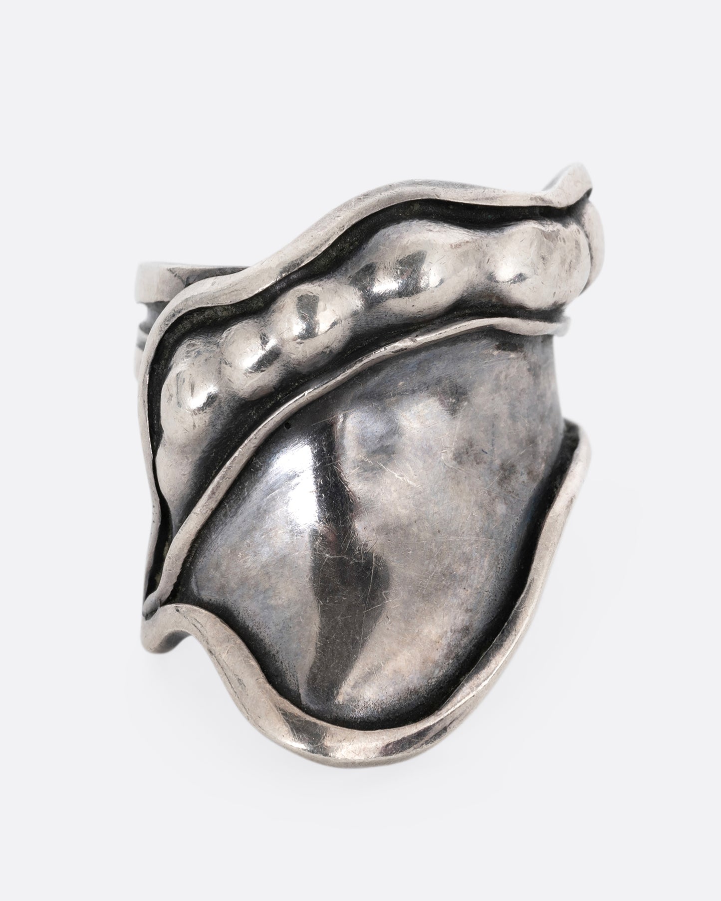 A silver leaf shaped wrap ring with silver drops along the top edge. Shown from the front.