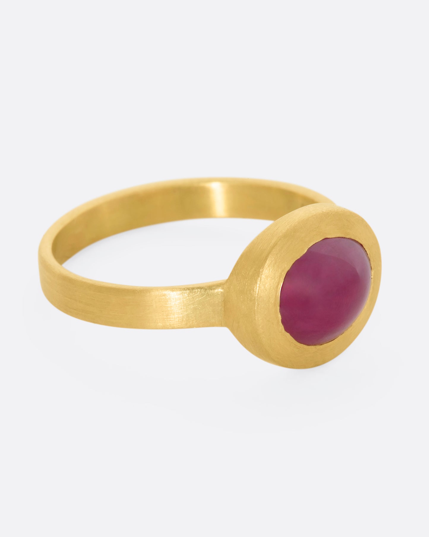 A yellow gold ring with a ruby cabochon. View from the side.