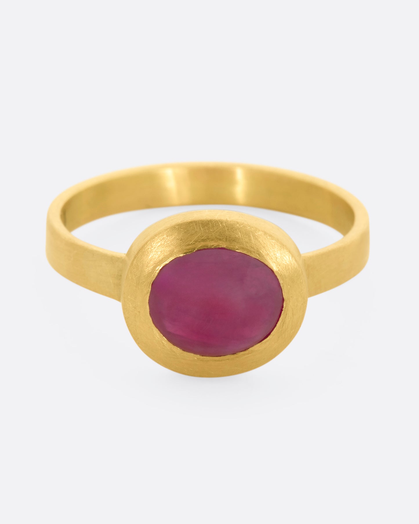 A yellow gold ring with a ruby cabochon. View from the front, slightly above.