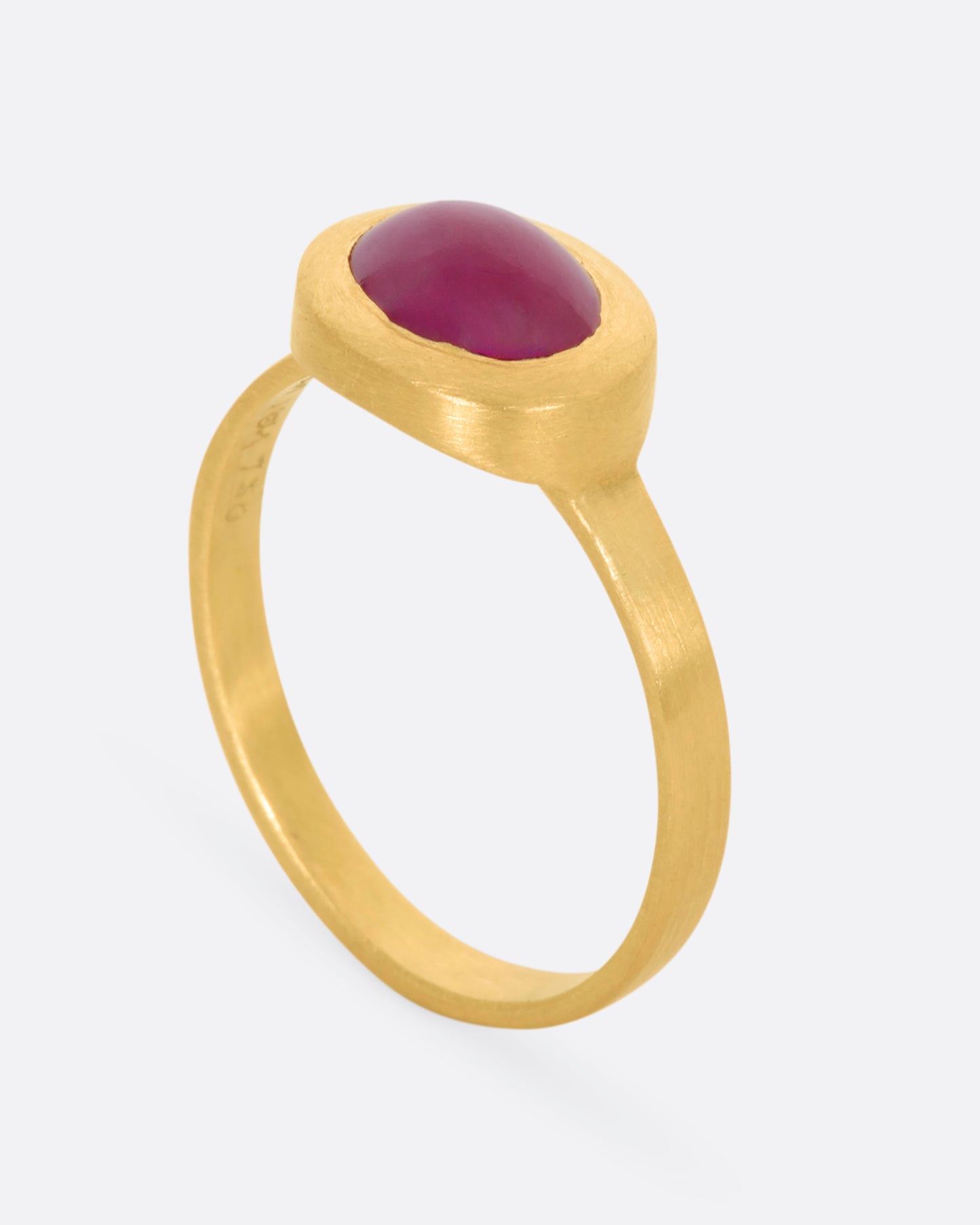 A yellow gold ring with a ruby cabochon. View from the side, standing up.