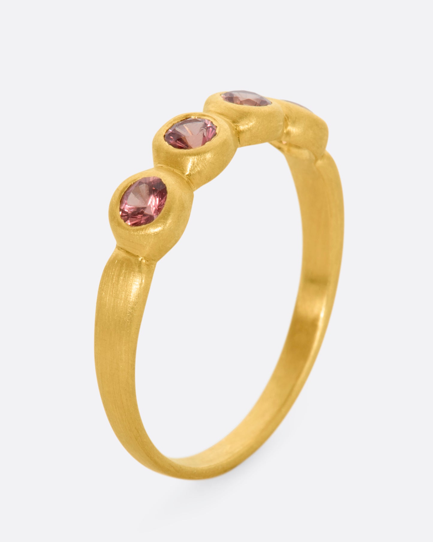 A matte yellow gold band with four 3mm orange sapphires. View standing.