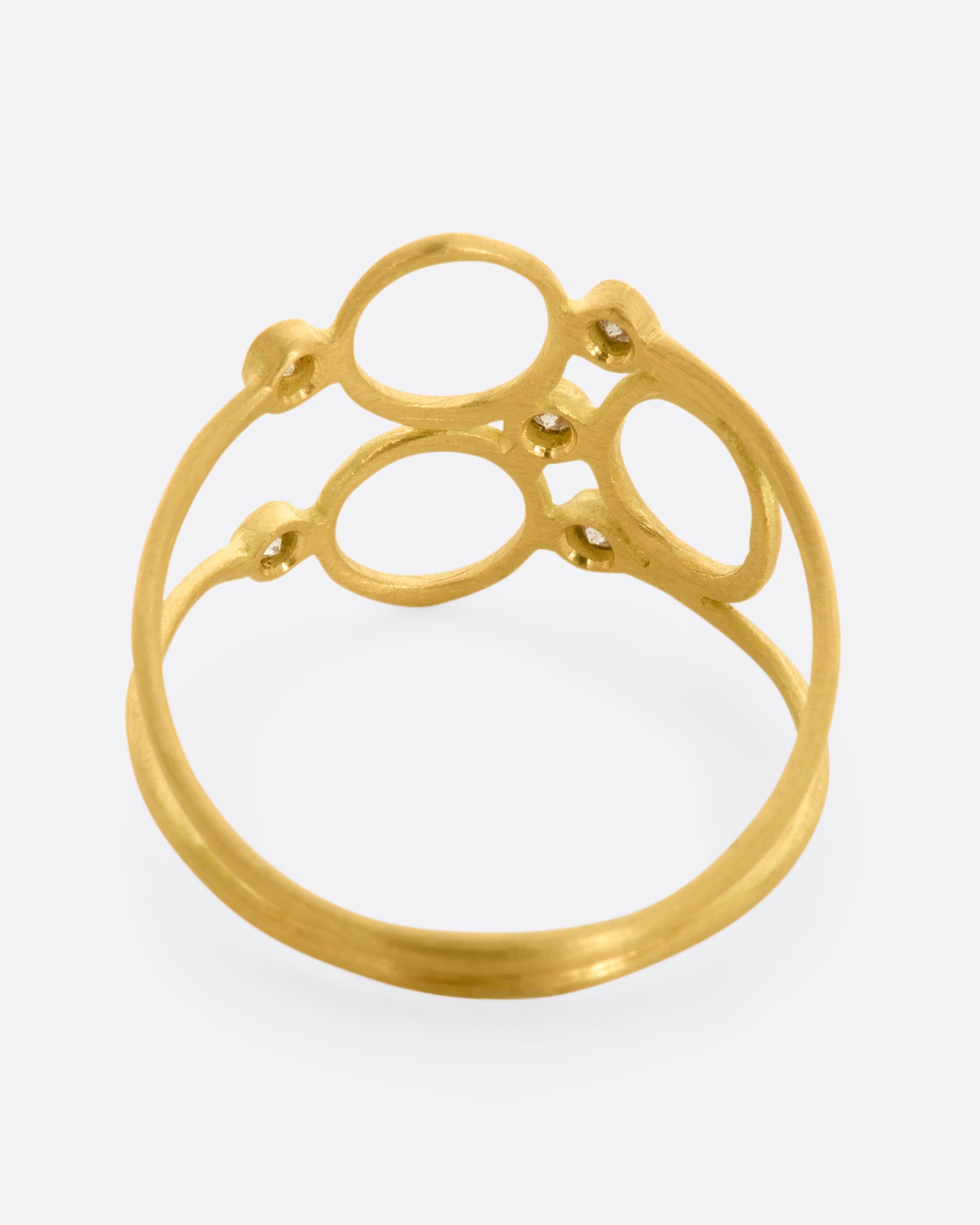 A yellow gold ring with three circles and five diamonds sandwiched between two thin bands. View from the back.