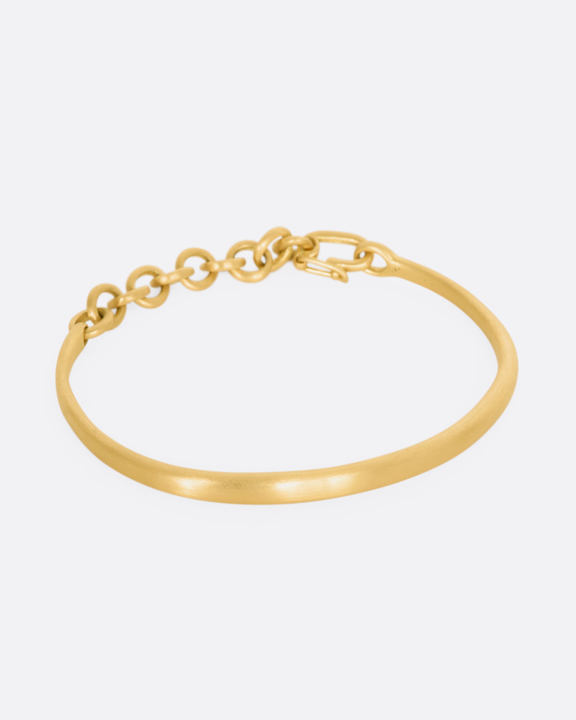 Yellow gold cuff bracelet with a chain closure.