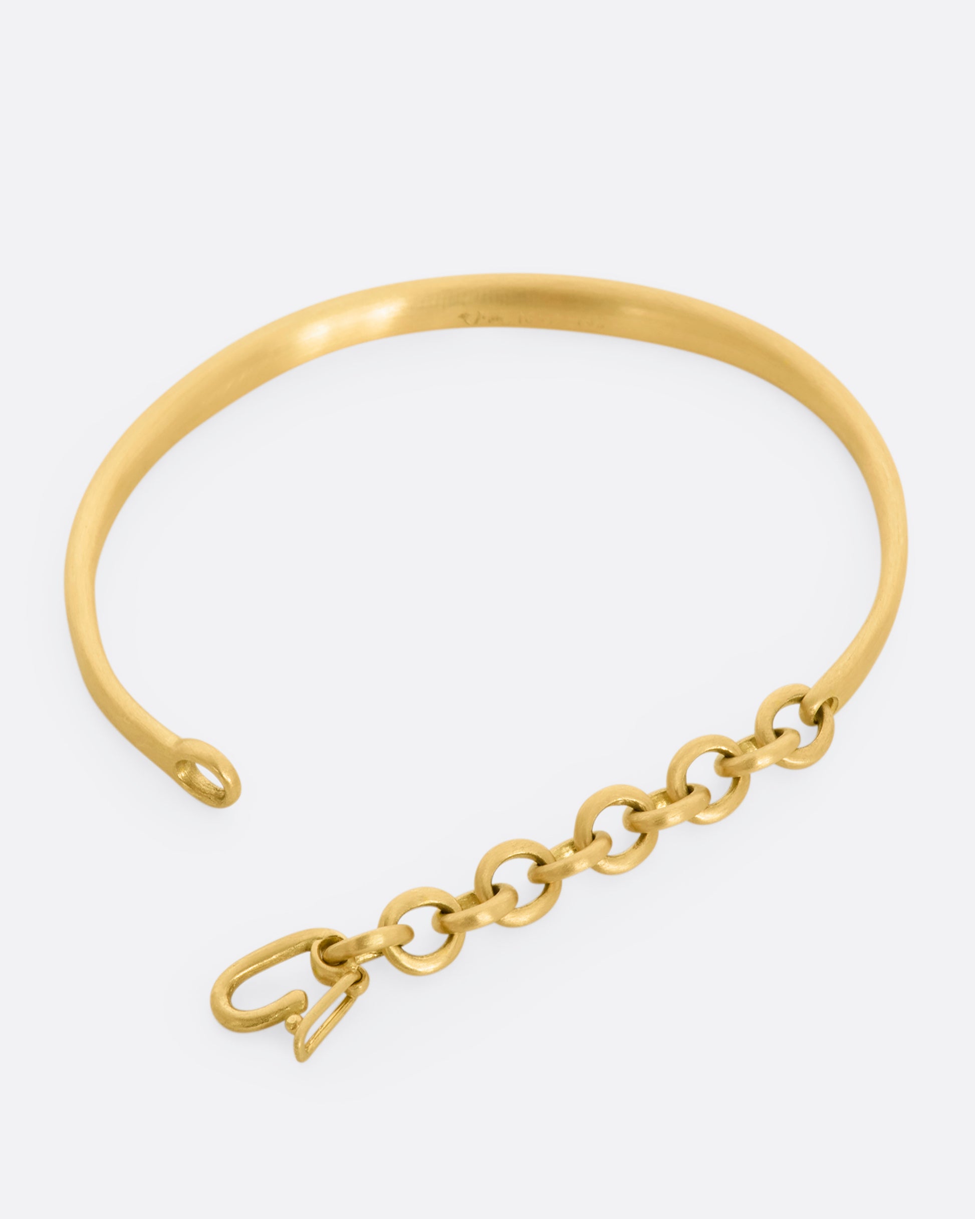 Yellow gold cuff bracelet with a chain closure.