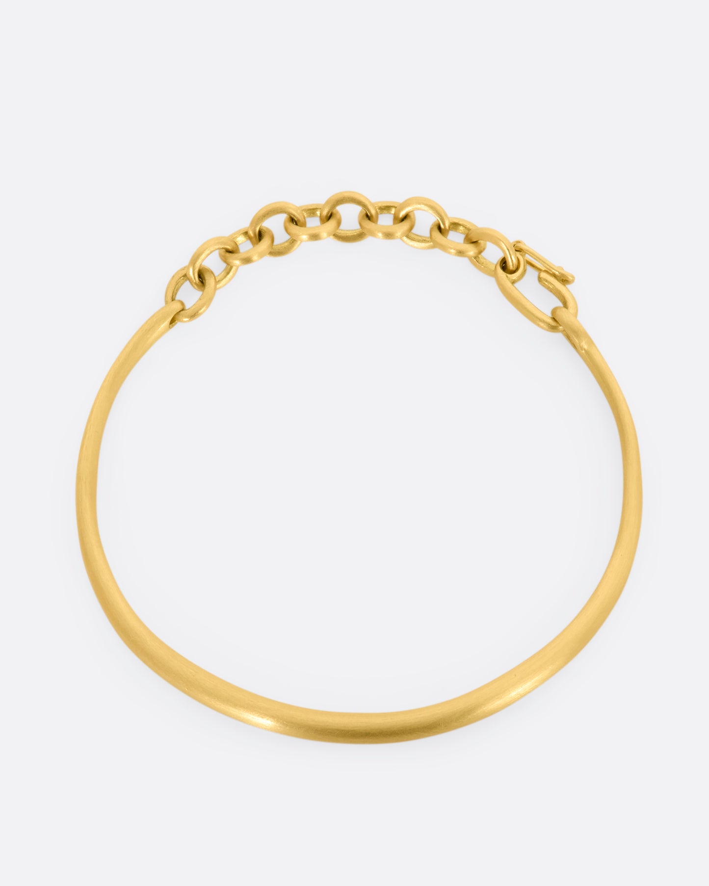 Yellow gold cuff bracelet with a chain closure.