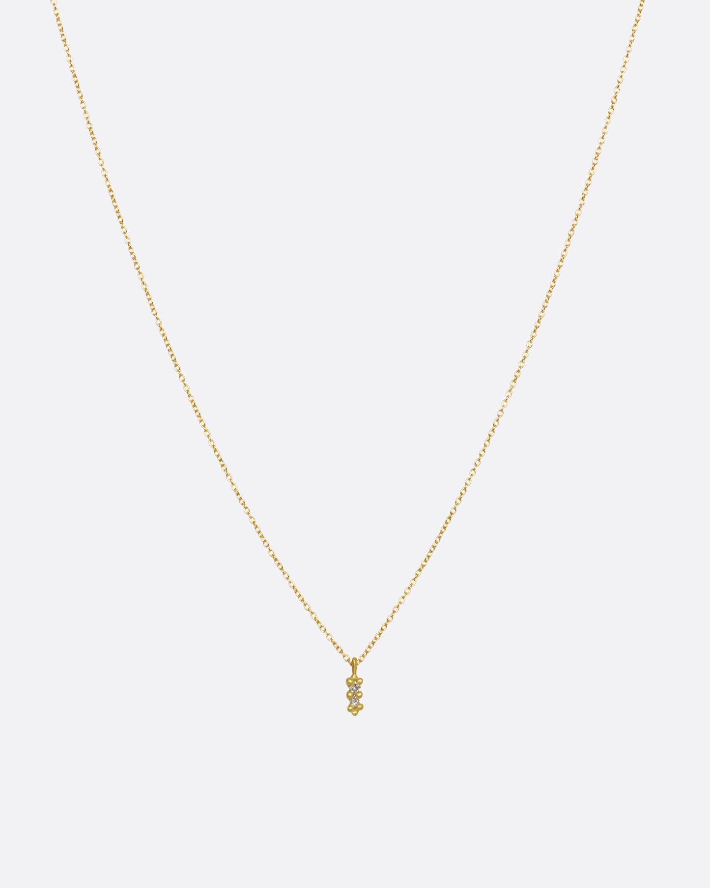 A yellow gold necklace with a double white diamond pendant. Shown from the front.