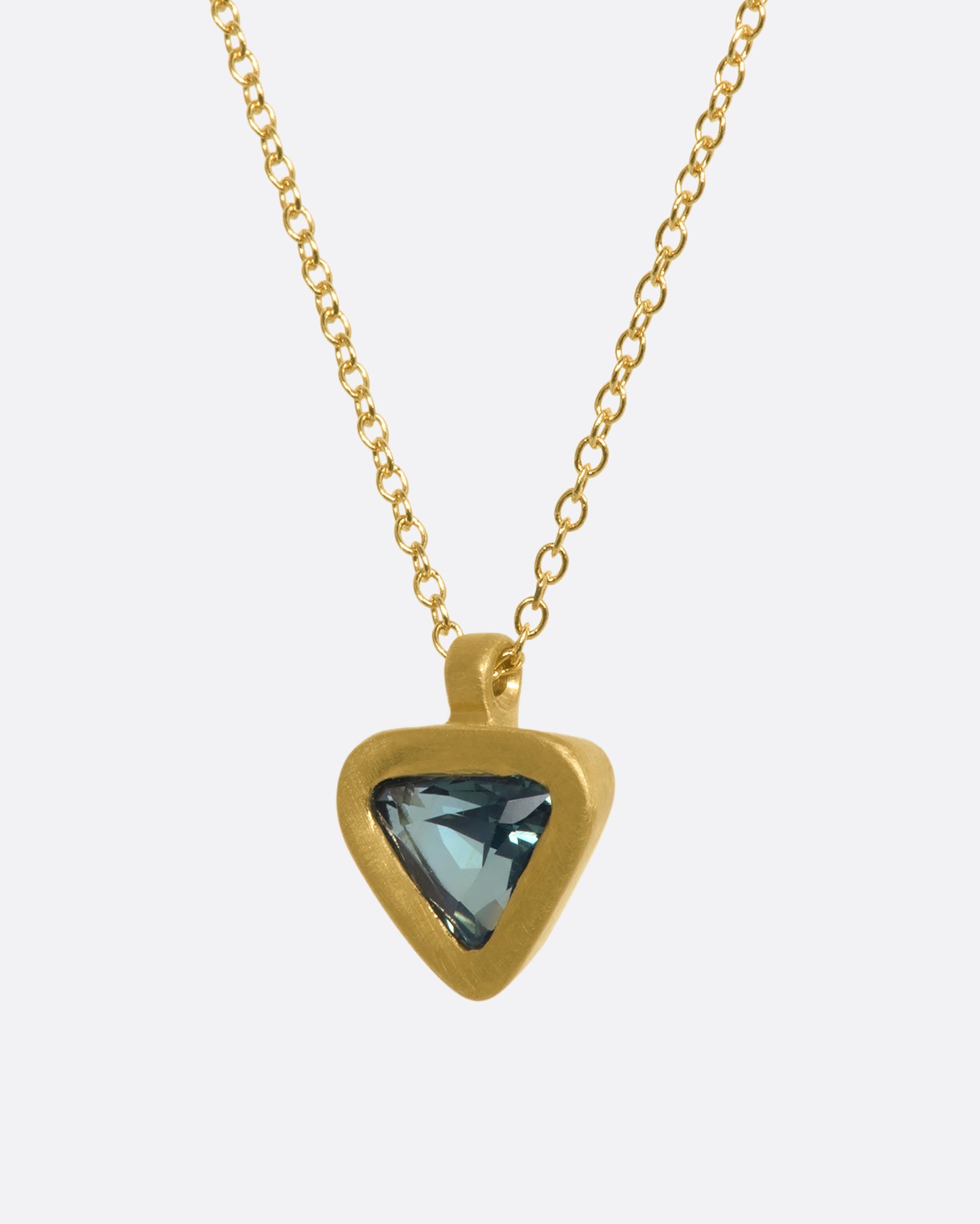 A yellow gold pendant with a triangle green sapphire pendant. View from the side.