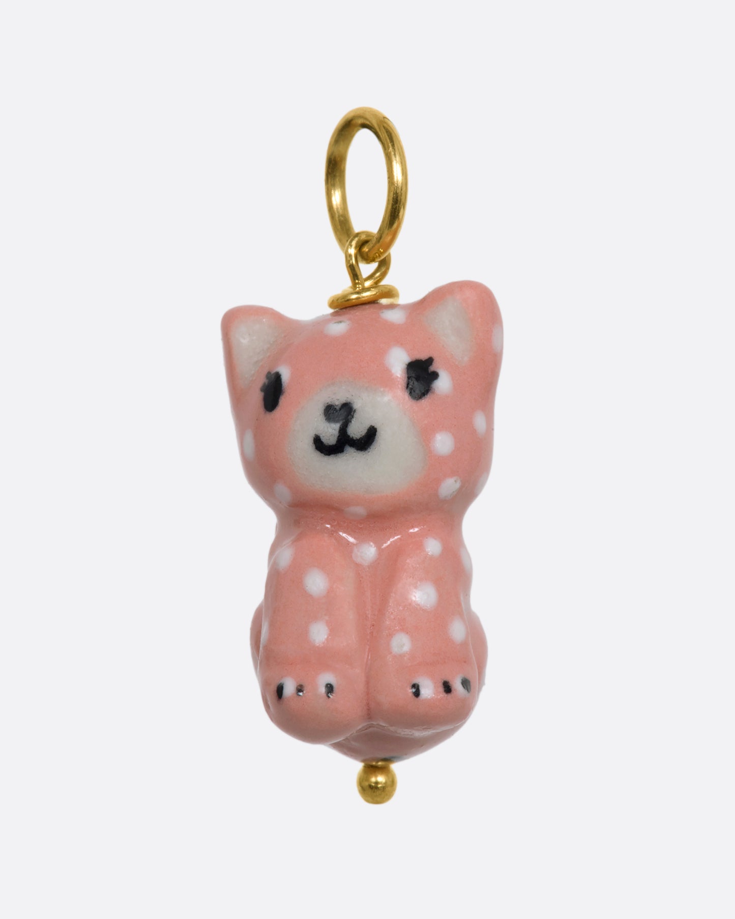 A three dimensional porcelain pink cat charm with white spots. View from the front.