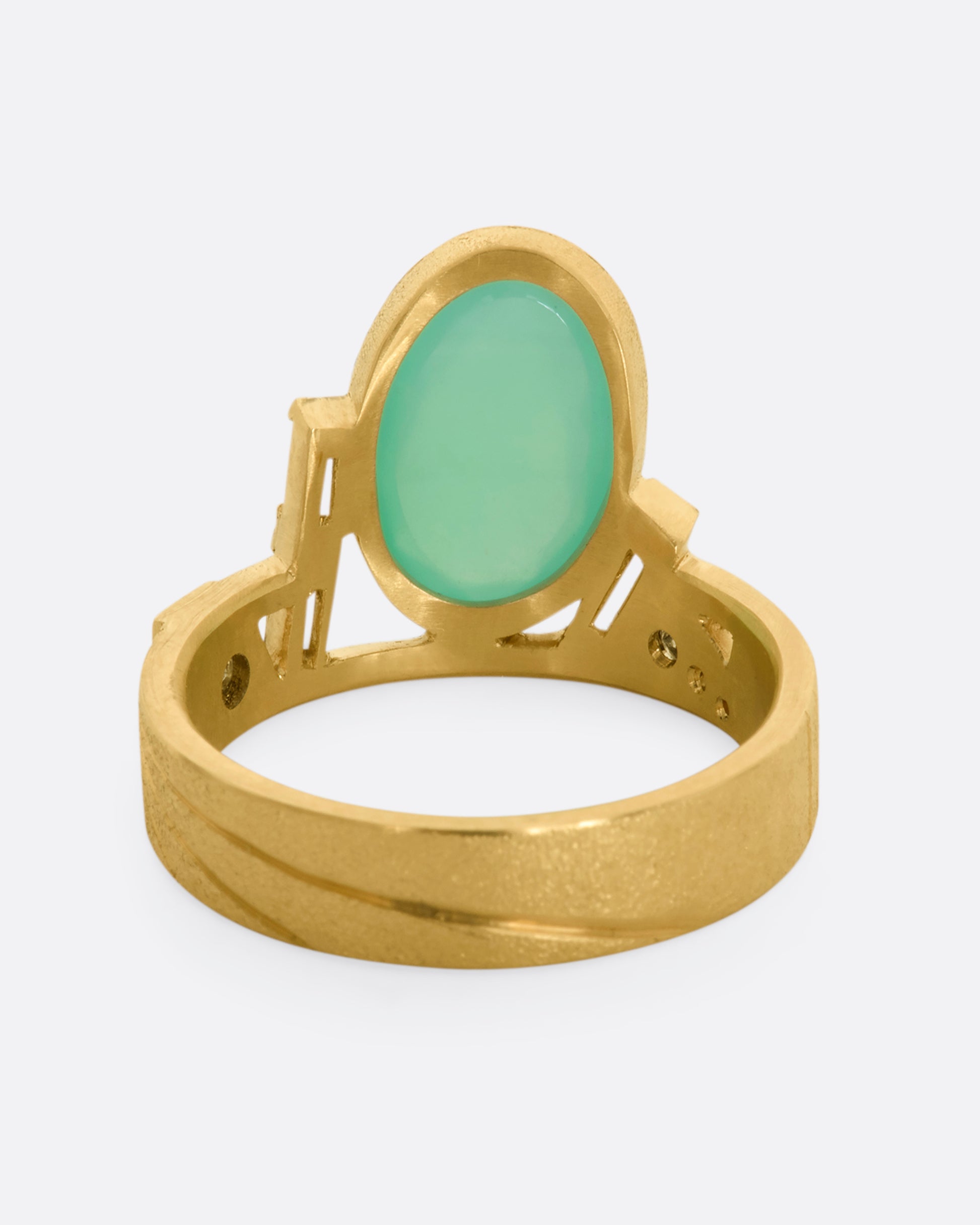 A yellow gold wide band ring with an oval chrysoprase, stacked baguette and round diamonds. View from the back.