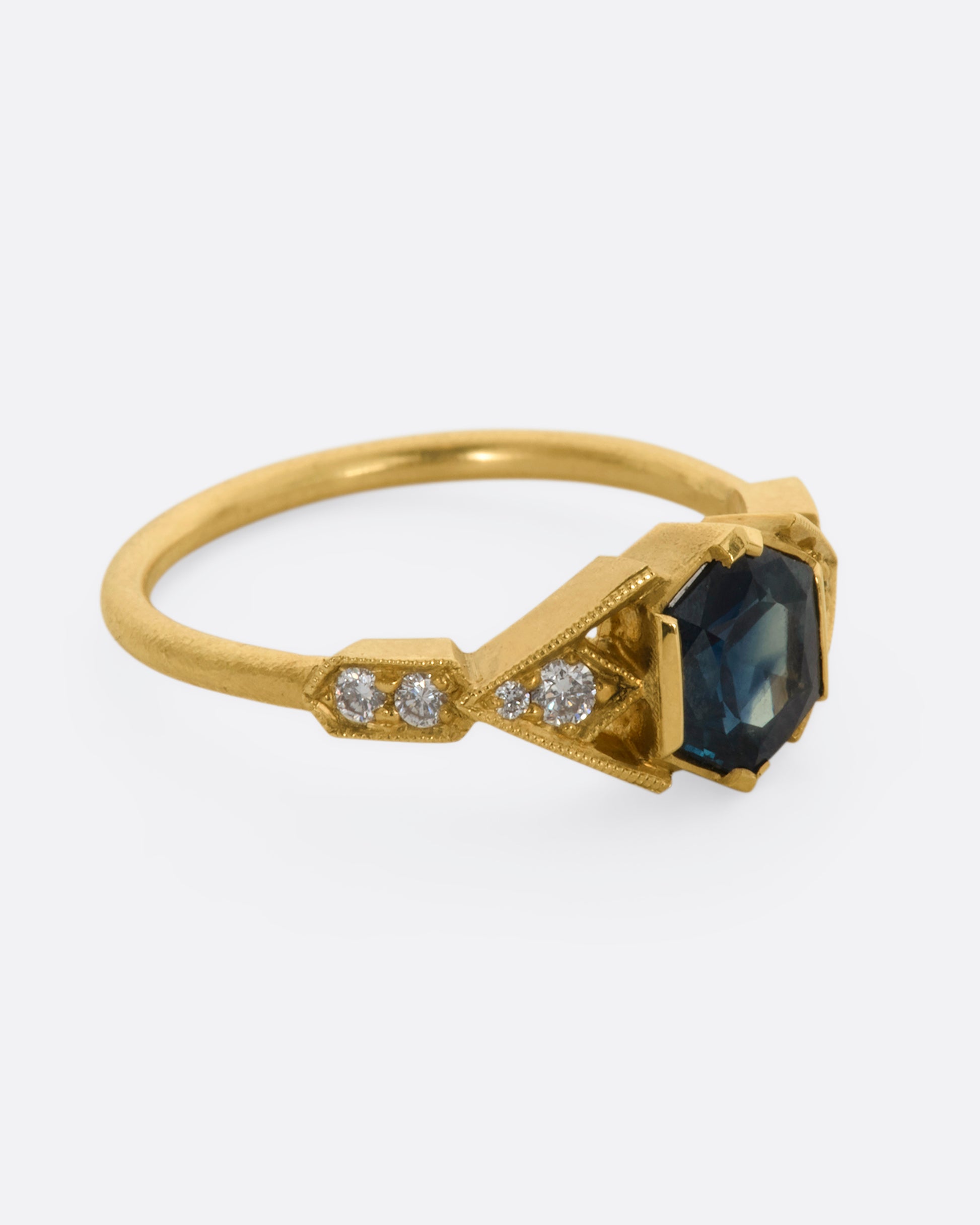 A yellow gold ring with deep teal sapphire and diamonds. View from the alternate side.