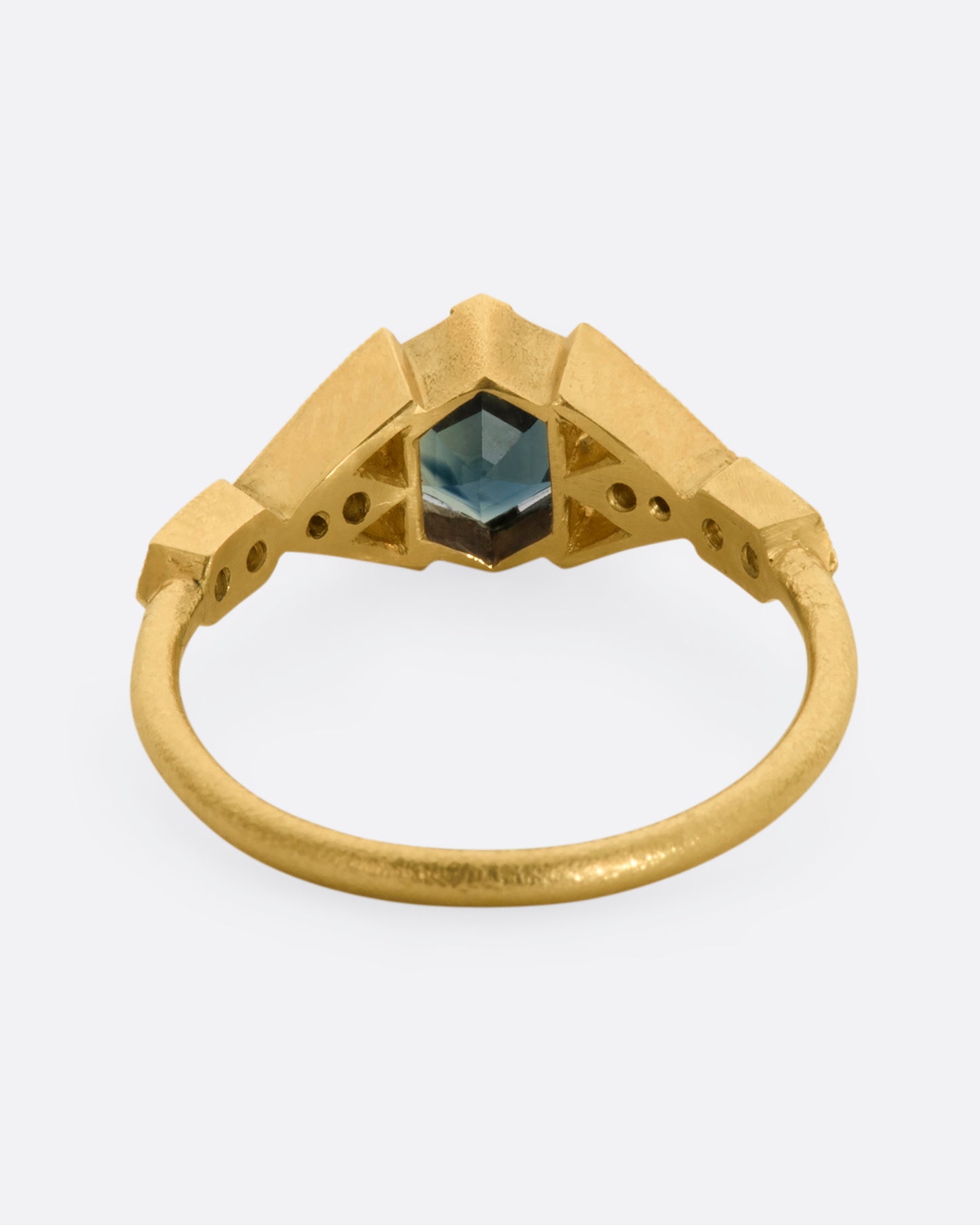 A yellow gold ring with deep teal sapphire and diamonds. View from the back.