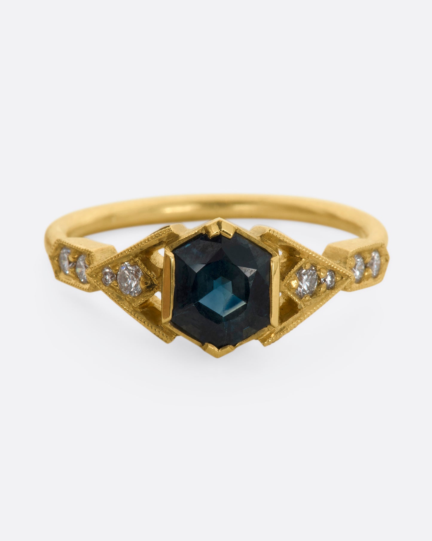 A yellow gold ring with deep teal sapphire and diamonds. View from the front.