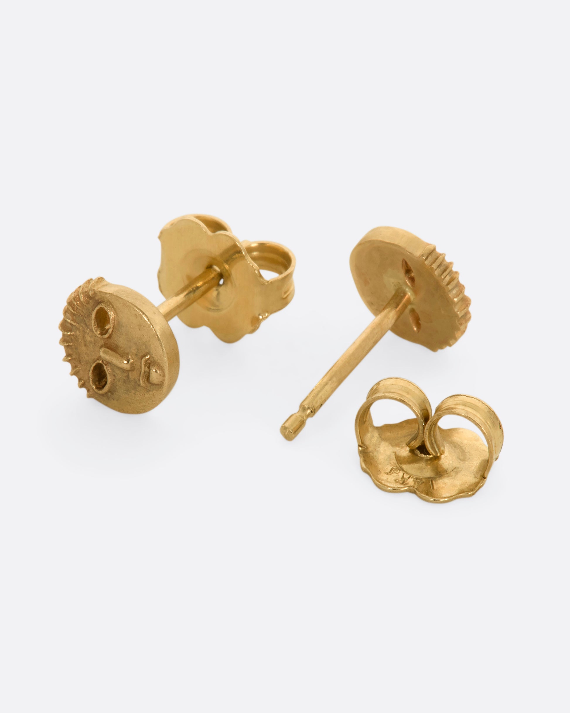 Yellow gold mask stud earrings. View laying flat showing the post and backing.