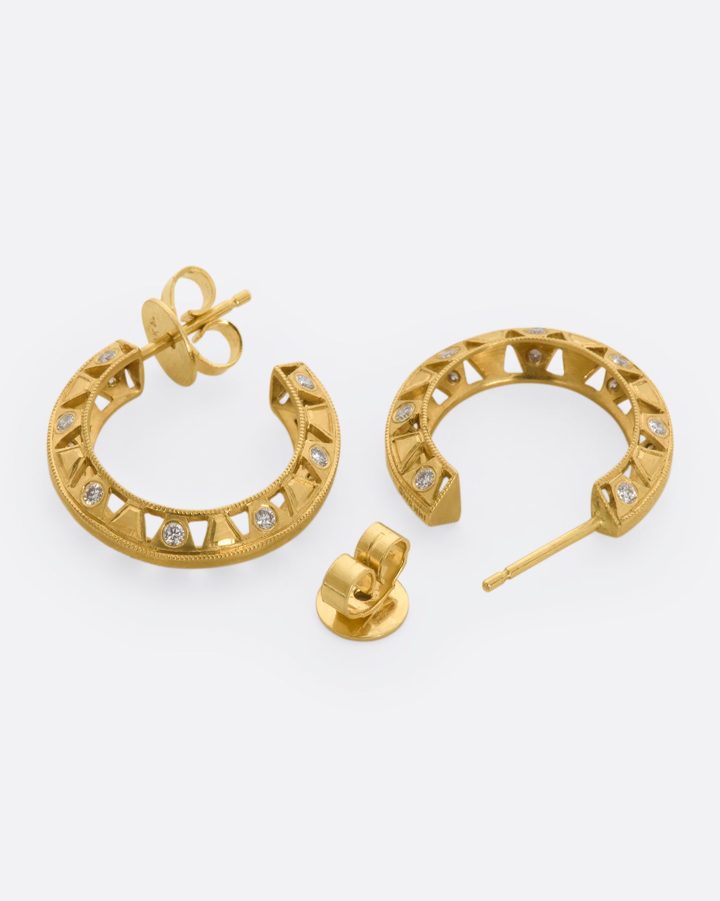 Intricate yellow gold hoop earrings with diamonds. View laying flat.