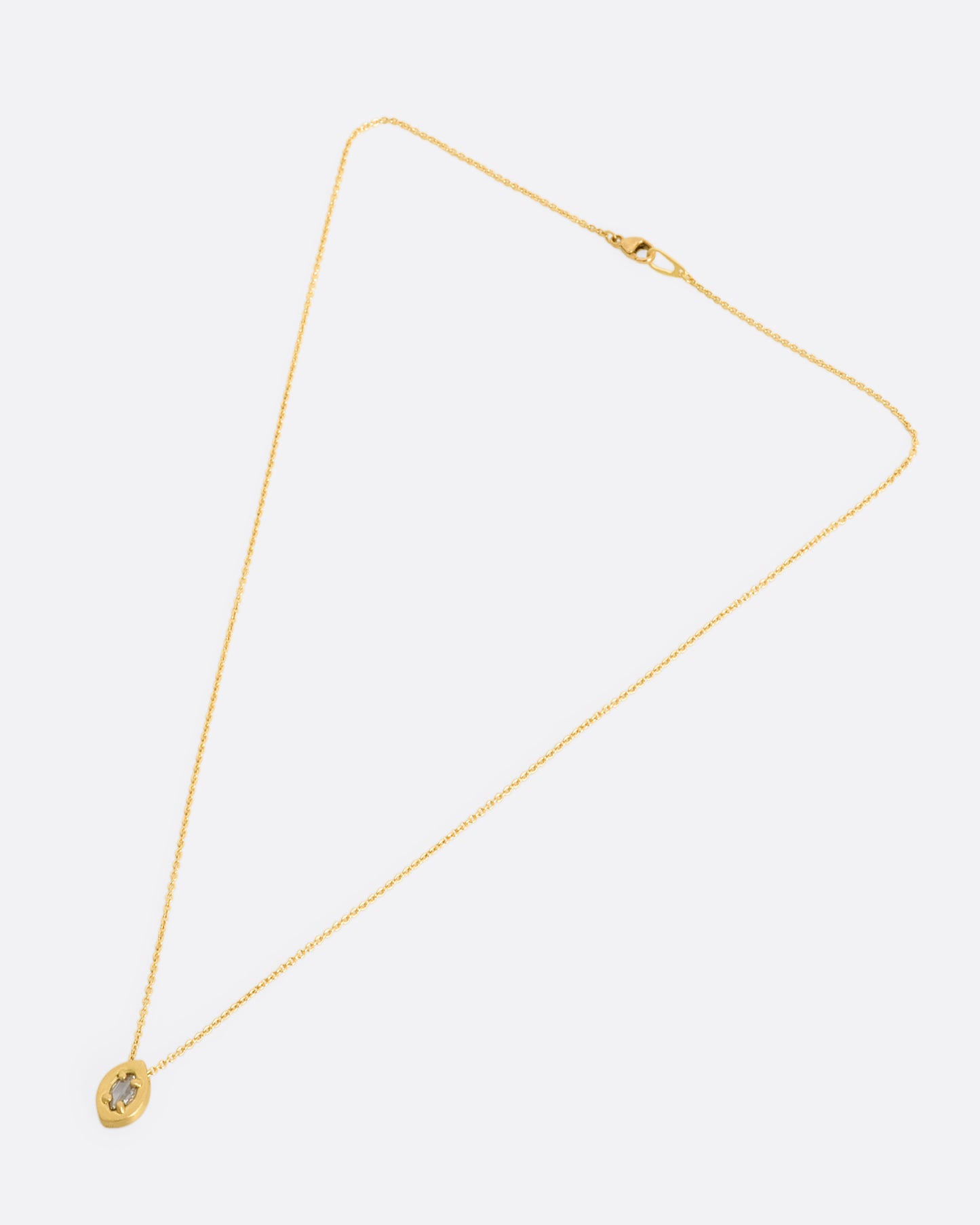 A yellow gold necklace with a prong set marquise diamond pendant. View of entire necklace laying flat.