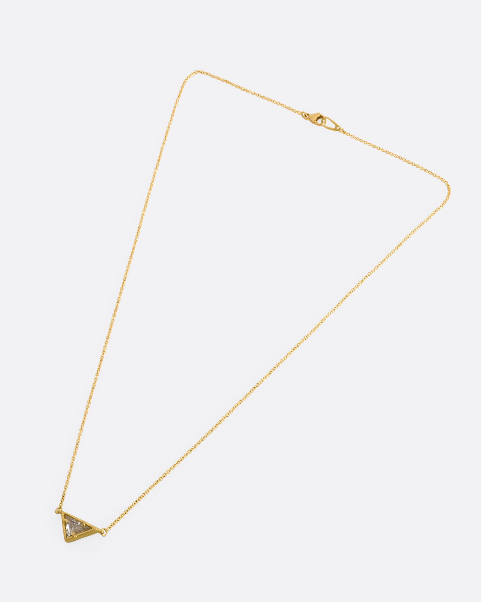 A yellow gold necklace with a triangular goshenite pendant. View laying flat.