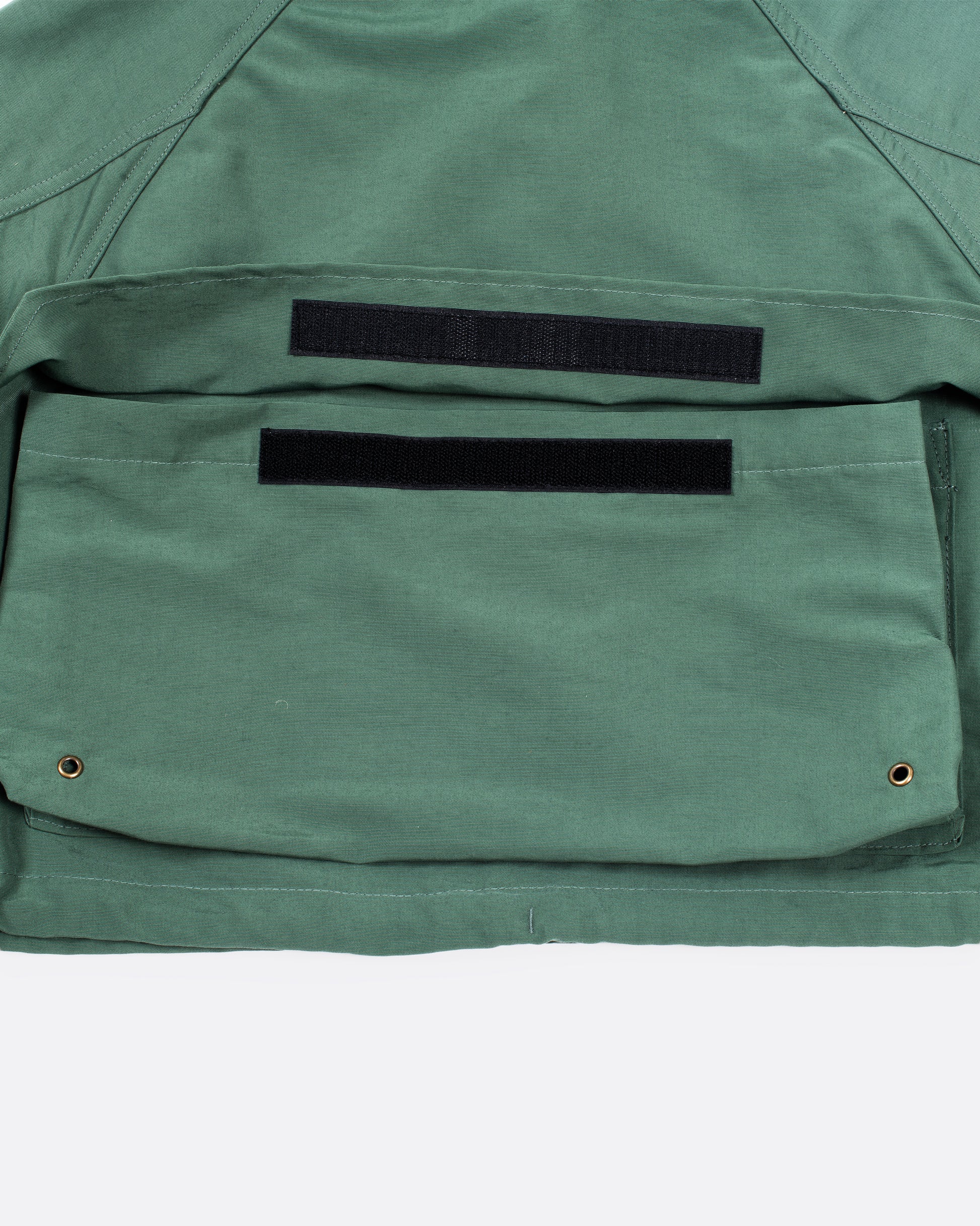 Cropped and hooded rain coat with two front pockets. Close up of the pocket.