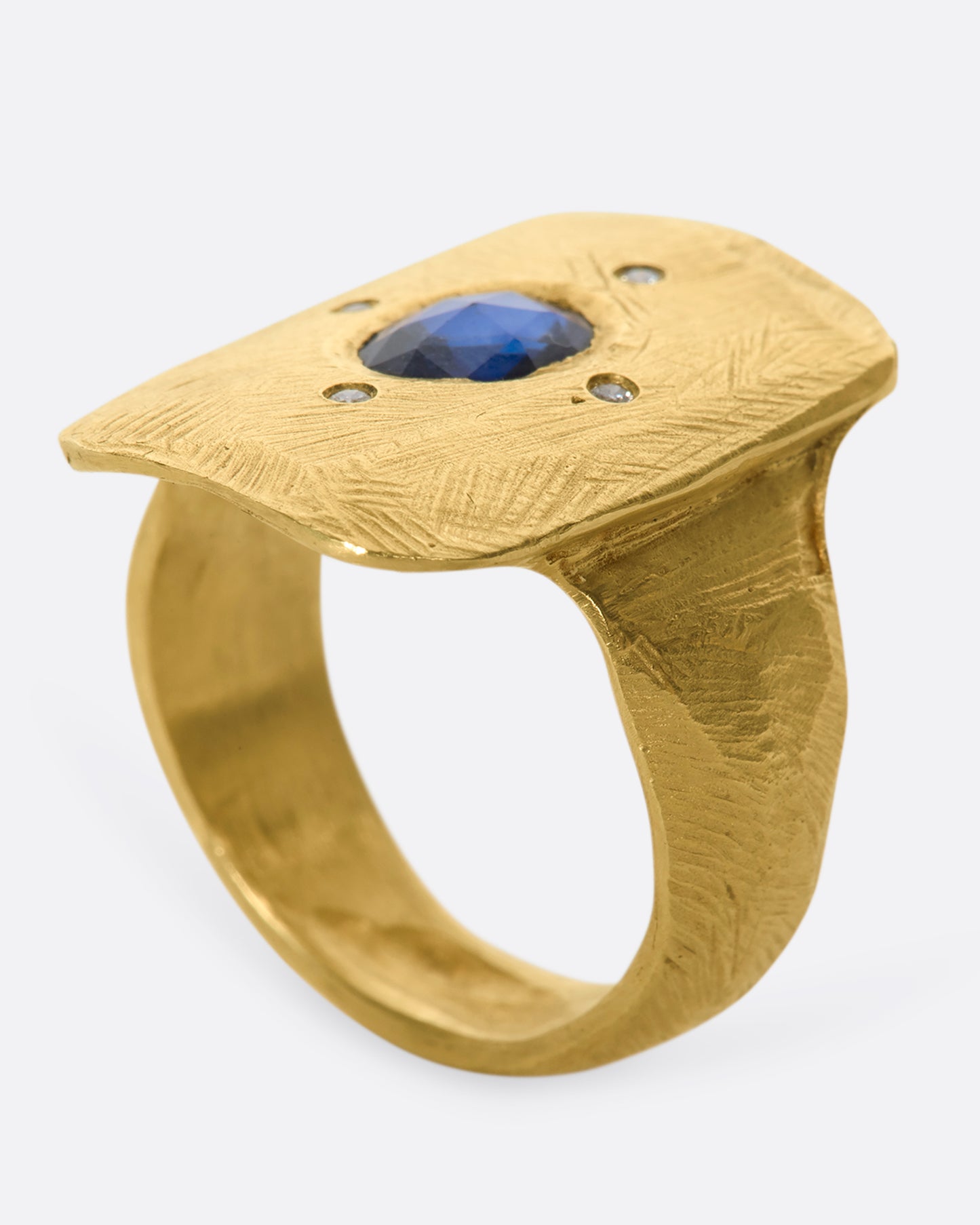 An 18k gold hand carved cocktail ring with a rose-cut, dark blue sapphire dotted with four star-like diamonds