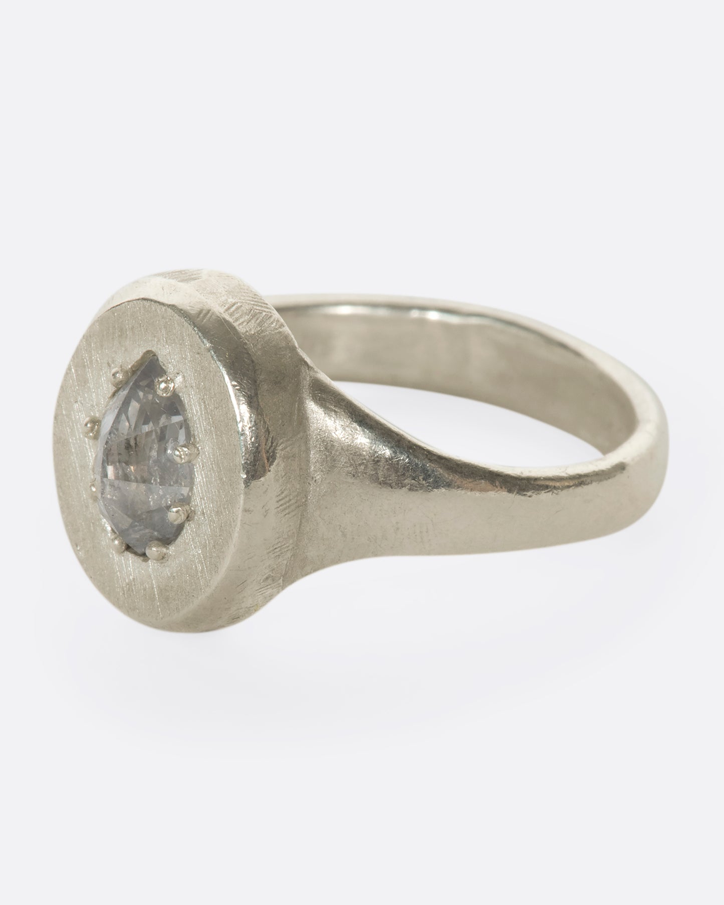 A sterling silver signet ring with a pear-shaped salt and pepper diamond secured with tiny prongs