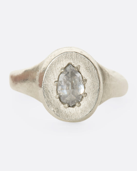 A sterling silver signet ring with a pear-shaped salt and pepper diamond secured with tiny prongs