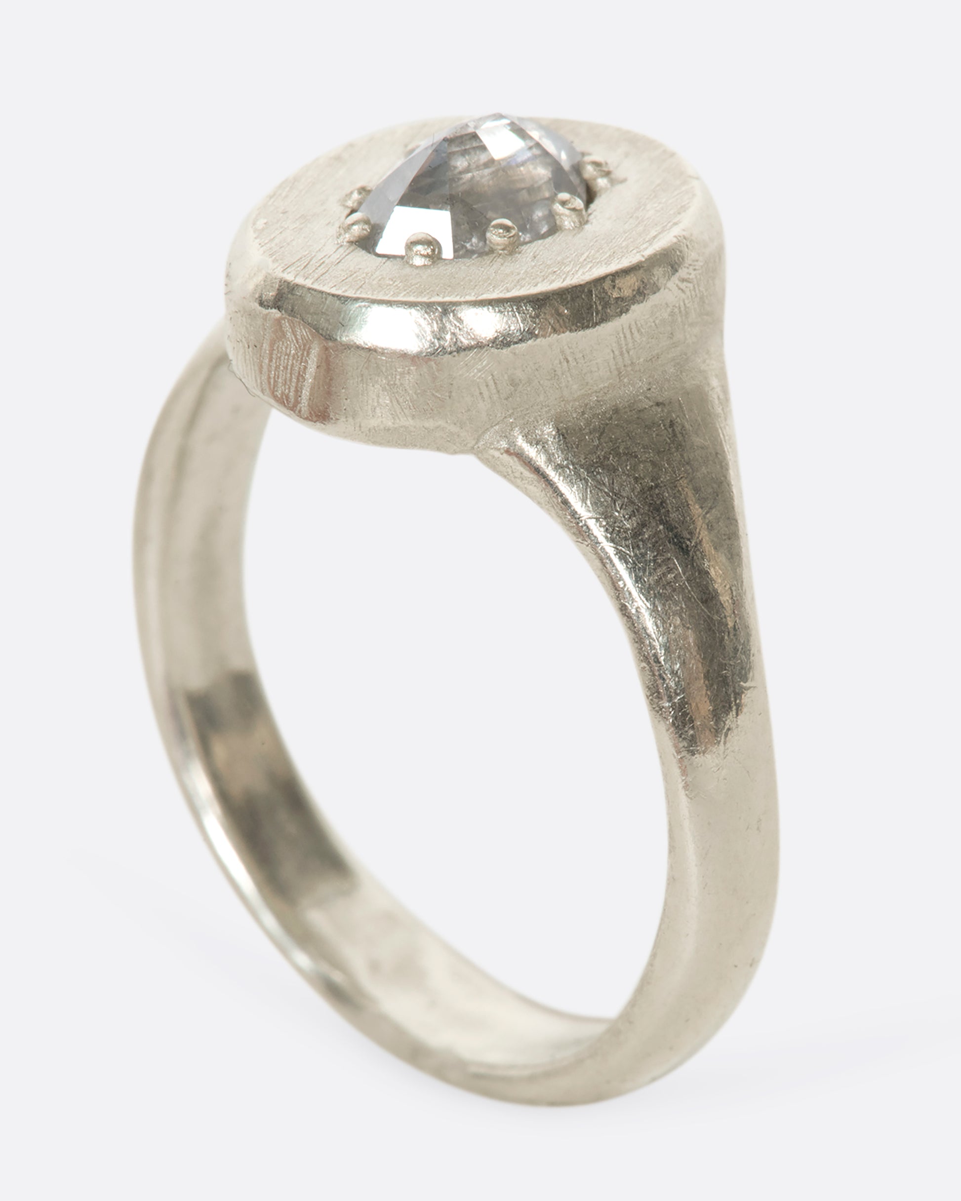 A sterling silver signet ring with a pear-shaped salt and pepper diamond secured with tiny prongs