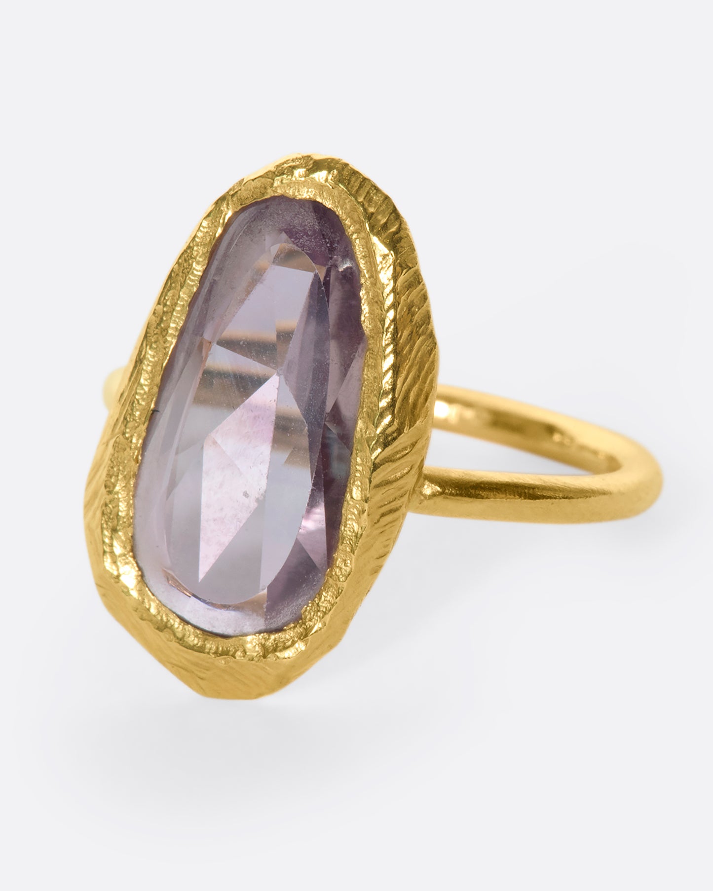 This truly unique freeform, rose-cut purple sapphire is nestled in a hand-carved 18k gold bezel setting