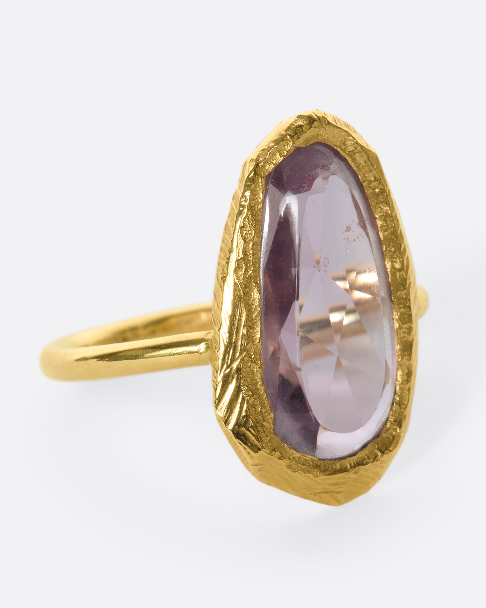 This truly unique freeform, rose-cut purple sapphire is nestled in a hand-carved 18k gold bezel setting