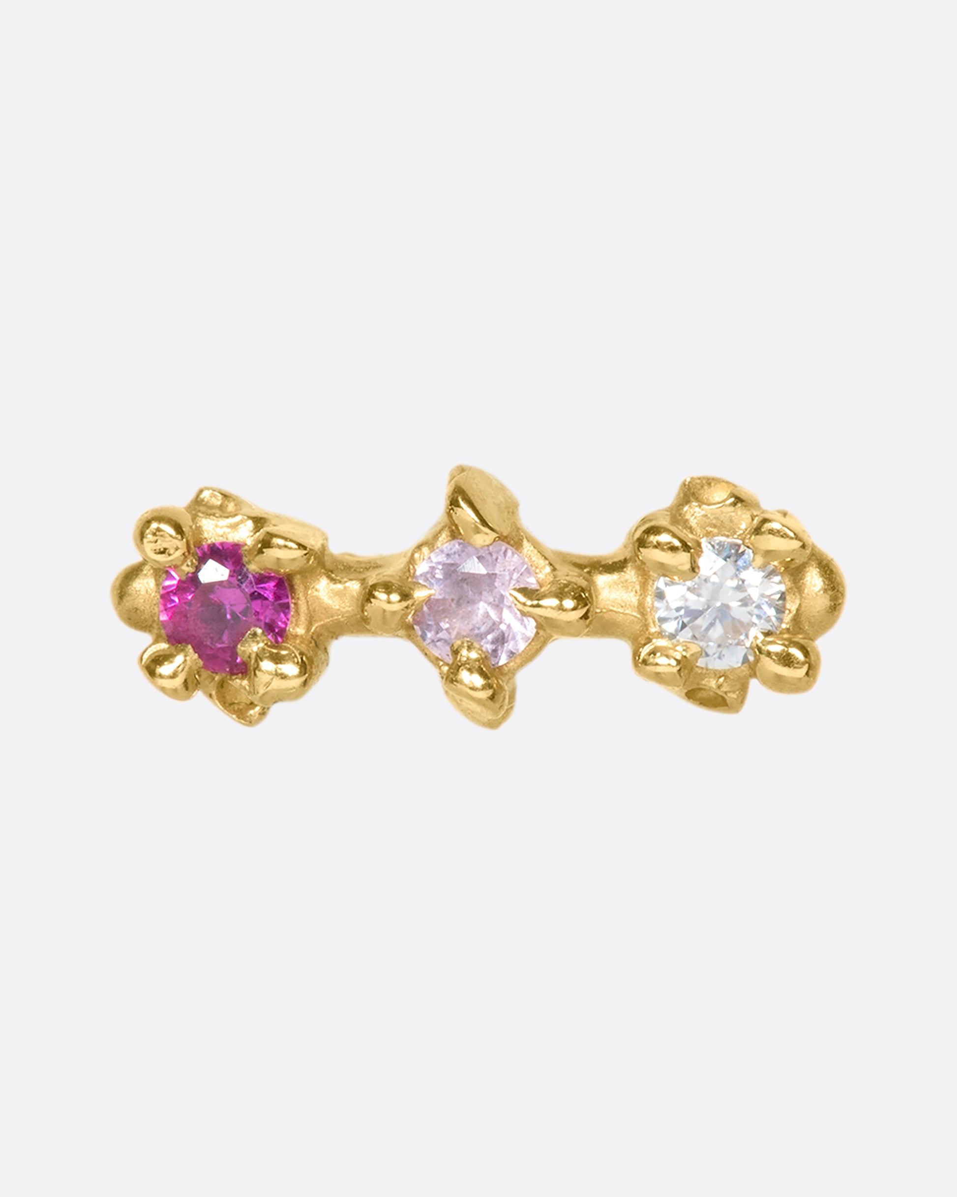 A 14k gold bar stud embellished with a ruby, pink sapphire, and diamond