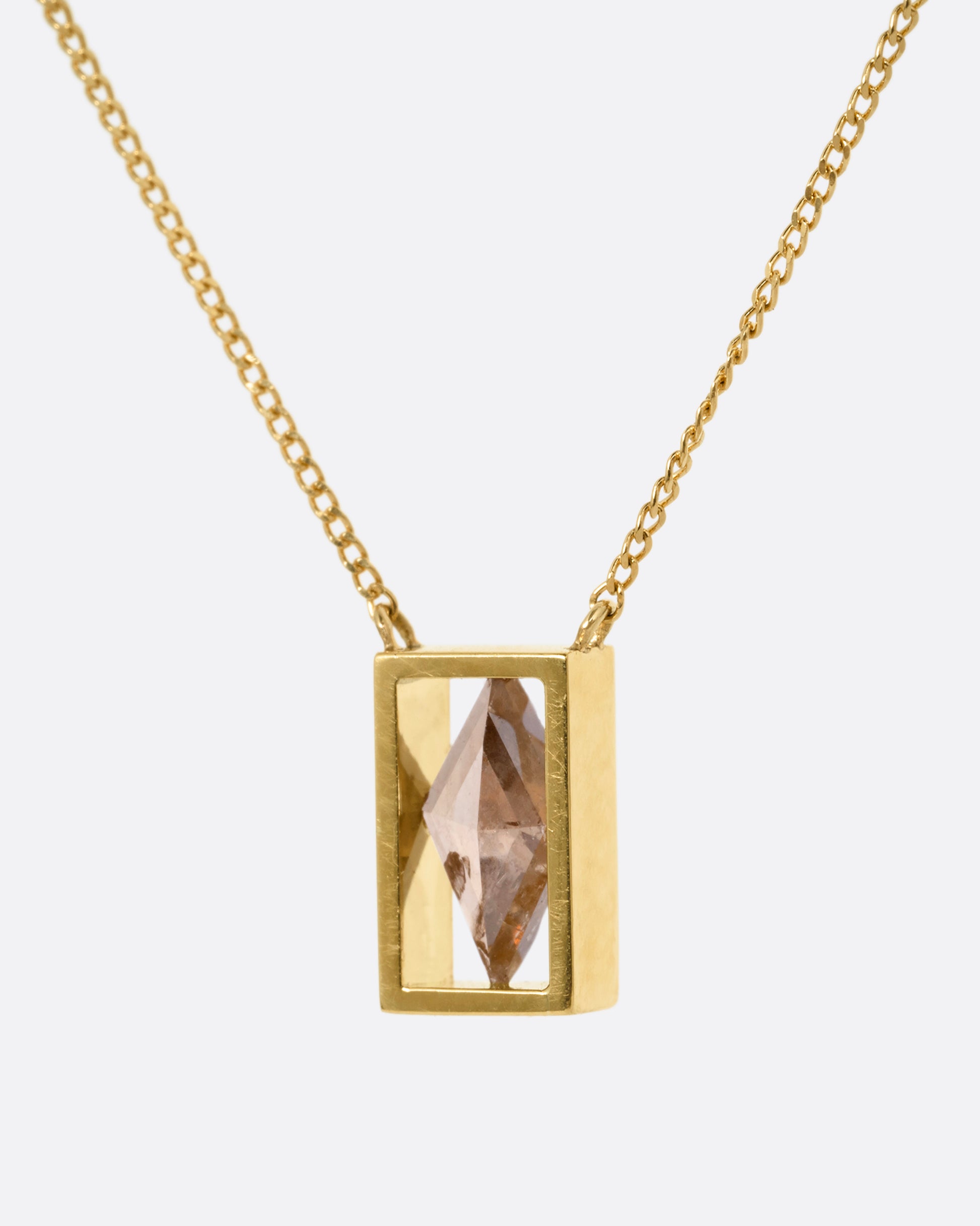 A yellow gold cable chain necklace with a rhombus shaped diamond in an open rectangular setting, shown from the side.