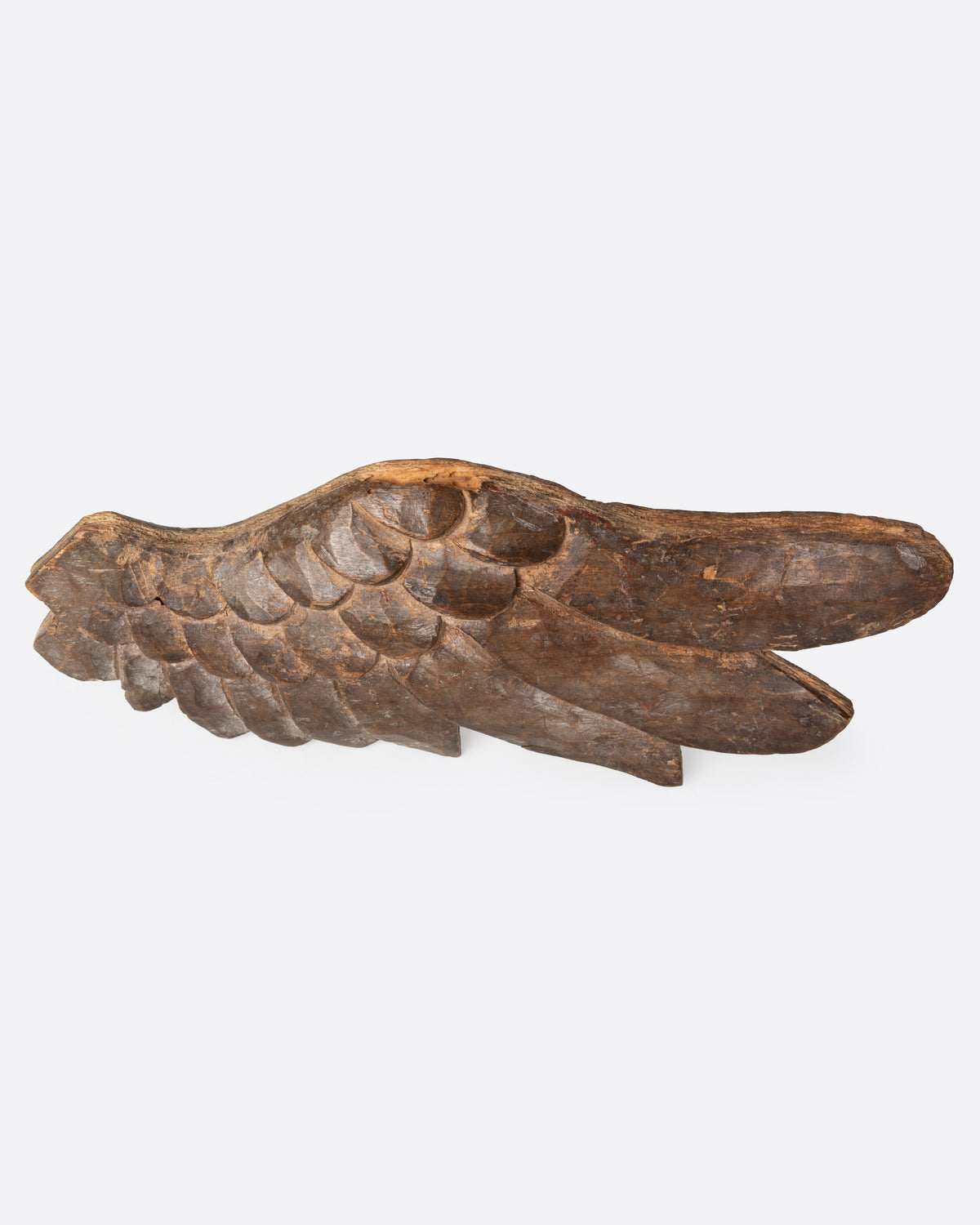 A wooden hand carved wing, shown from the side.
