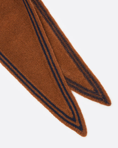 A close up of an orange knit scarf with a navy striped border.