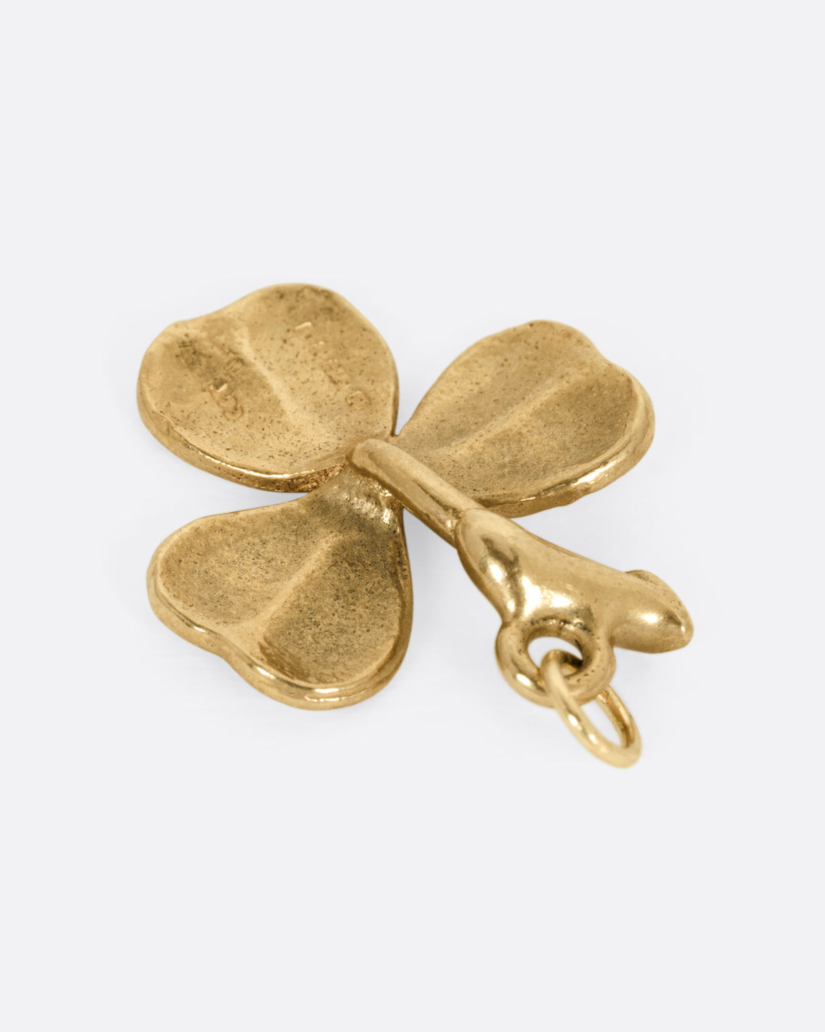 A yellow gold shamrock charm, shown from the back.