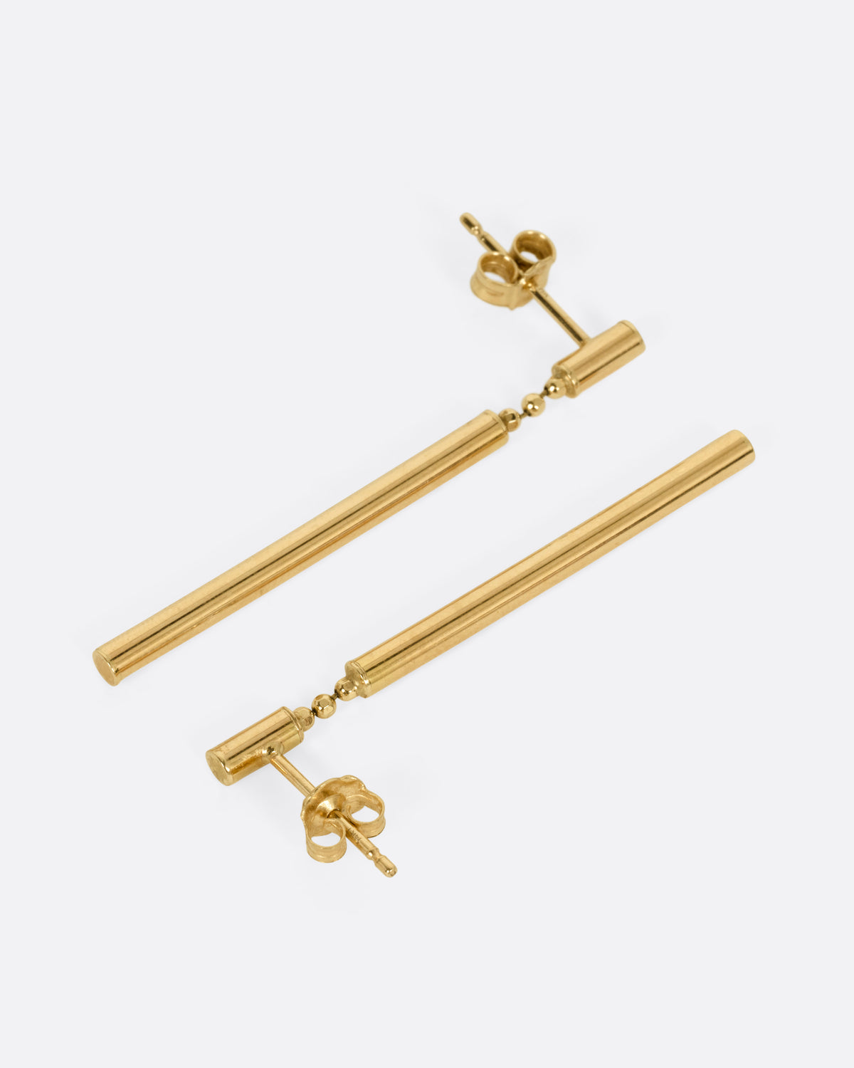 A pair of yellow gold drop earrings with a small cylindrical stud and a long, slender cylindrical dangle, shown from the side.
