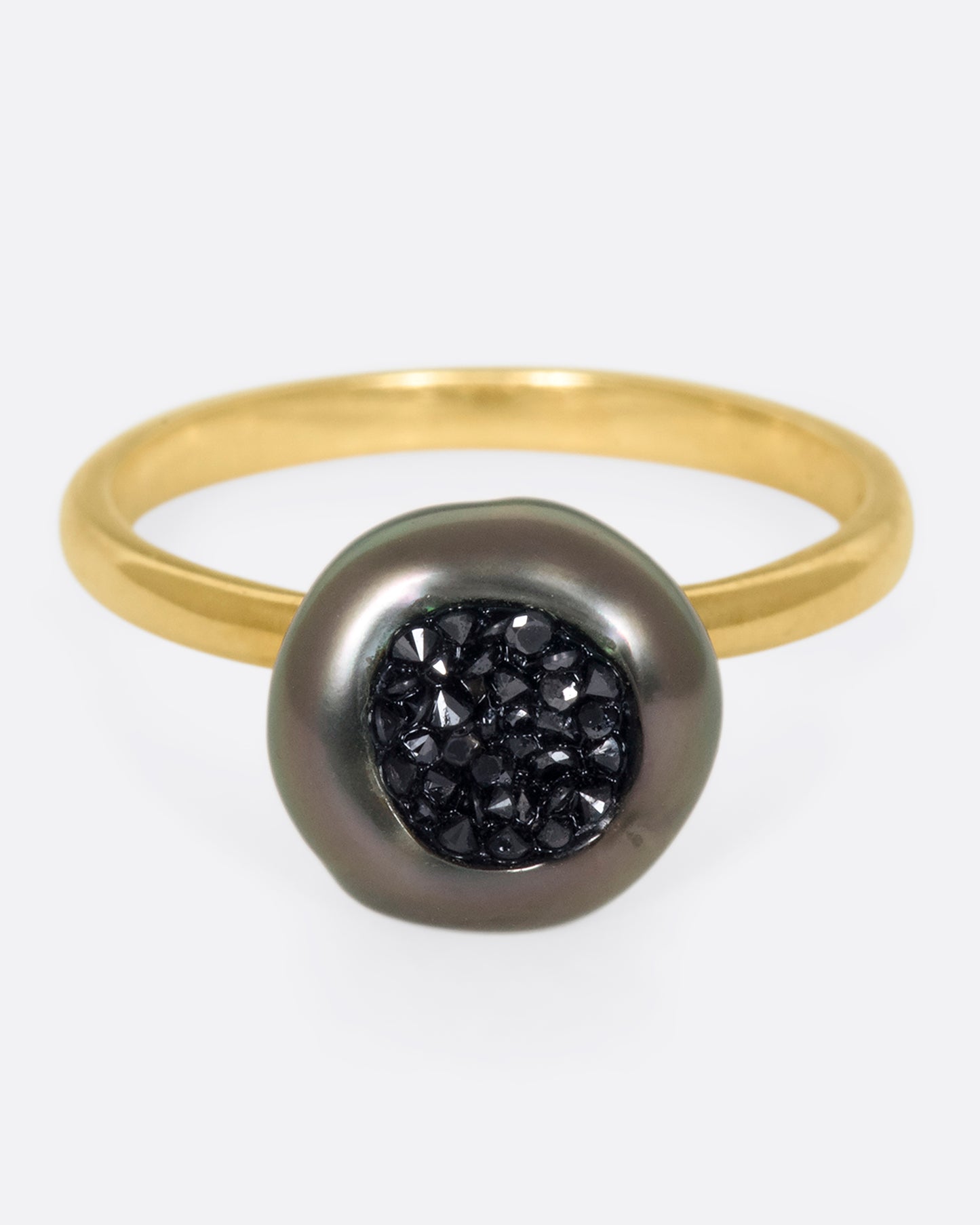 A 14k gold band with a carved Tahitian keshi pearl lined with black diamonds