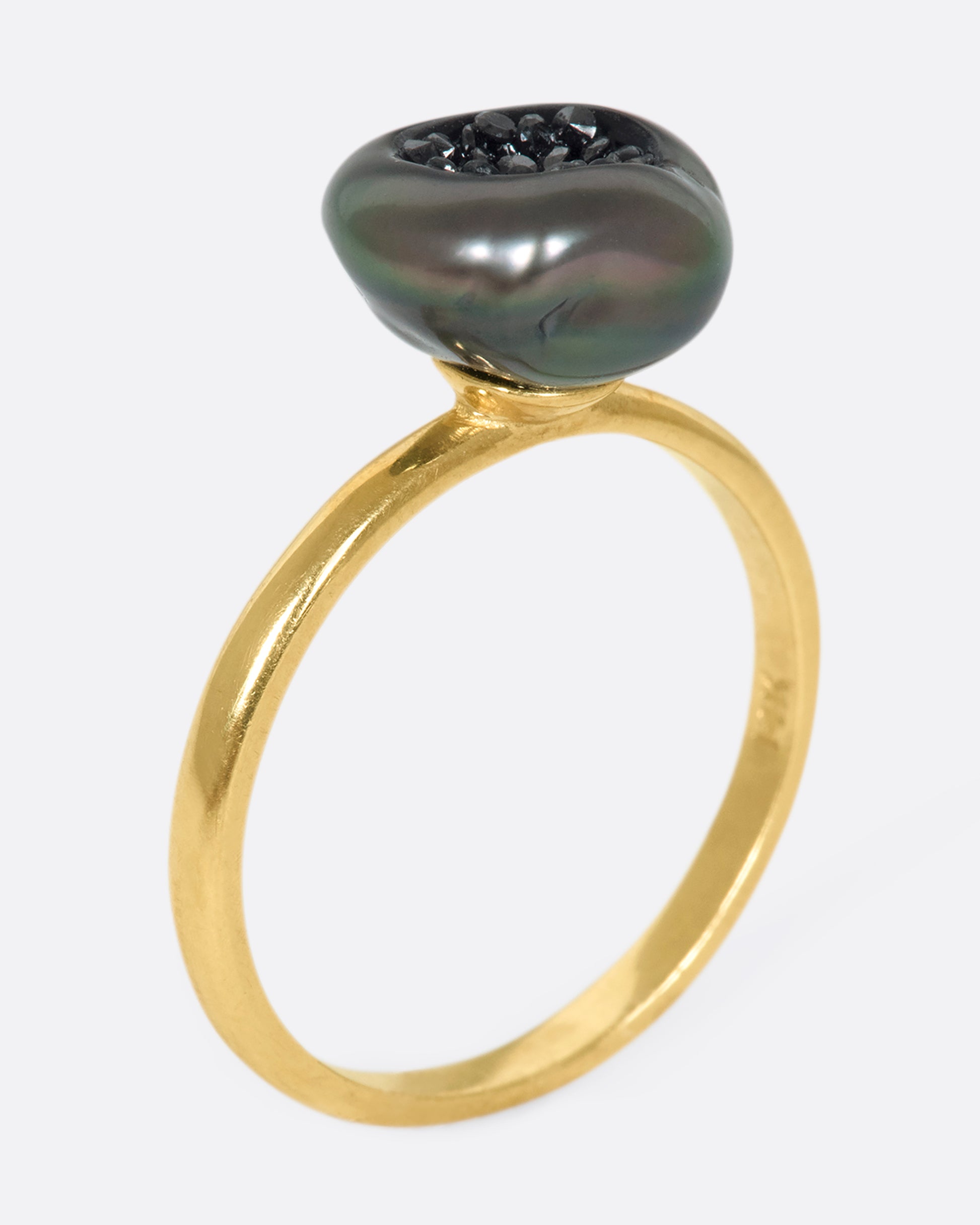 A 14k gold band with a carved Tahitian keshi pearl lined with black diamonds